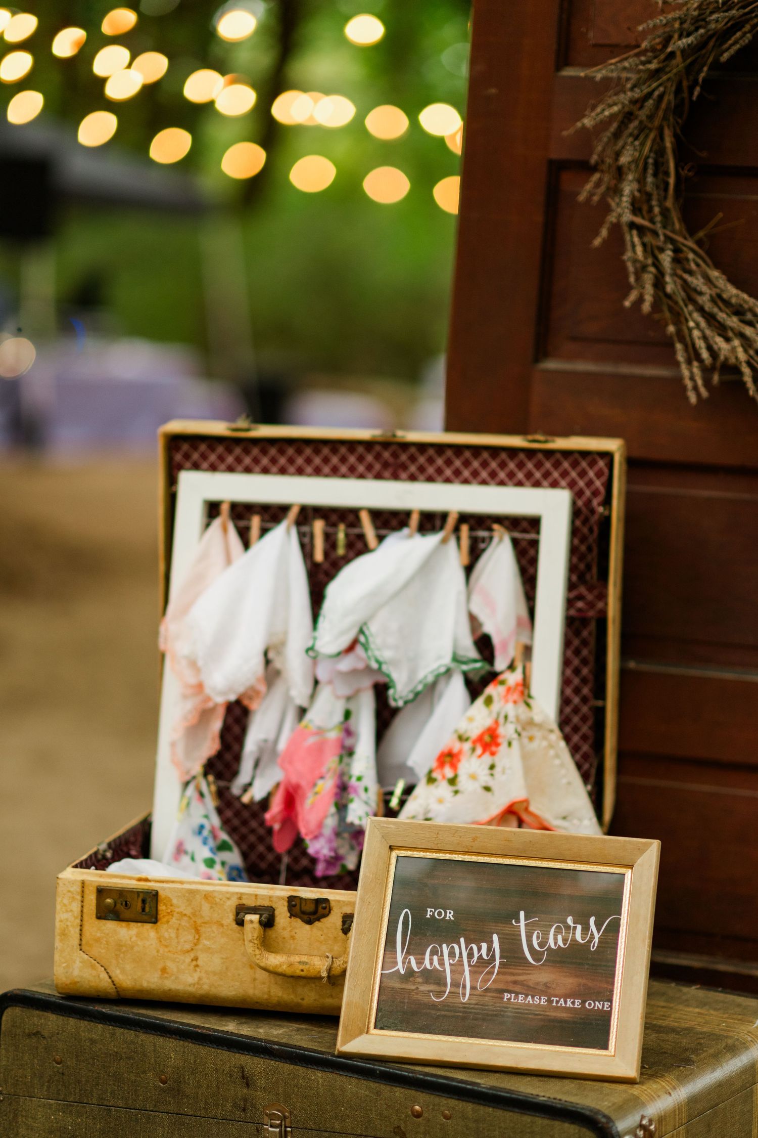 Vintage suitcase wedding display with colorful handkerchiefs and happy tears sign for wedding guests.
