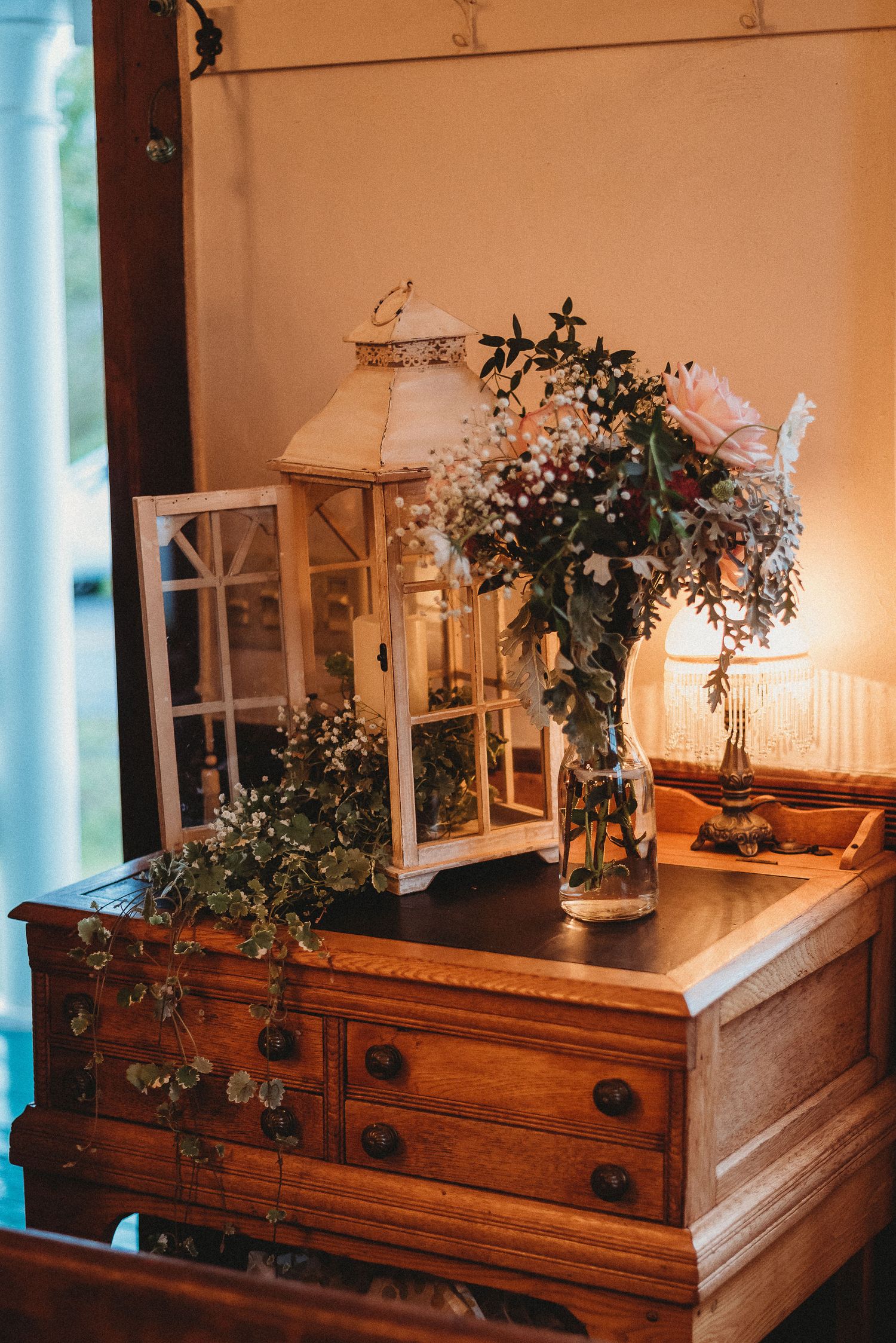 Vintage lanterns and floral arrangements displayed on an antique wooden dresser.