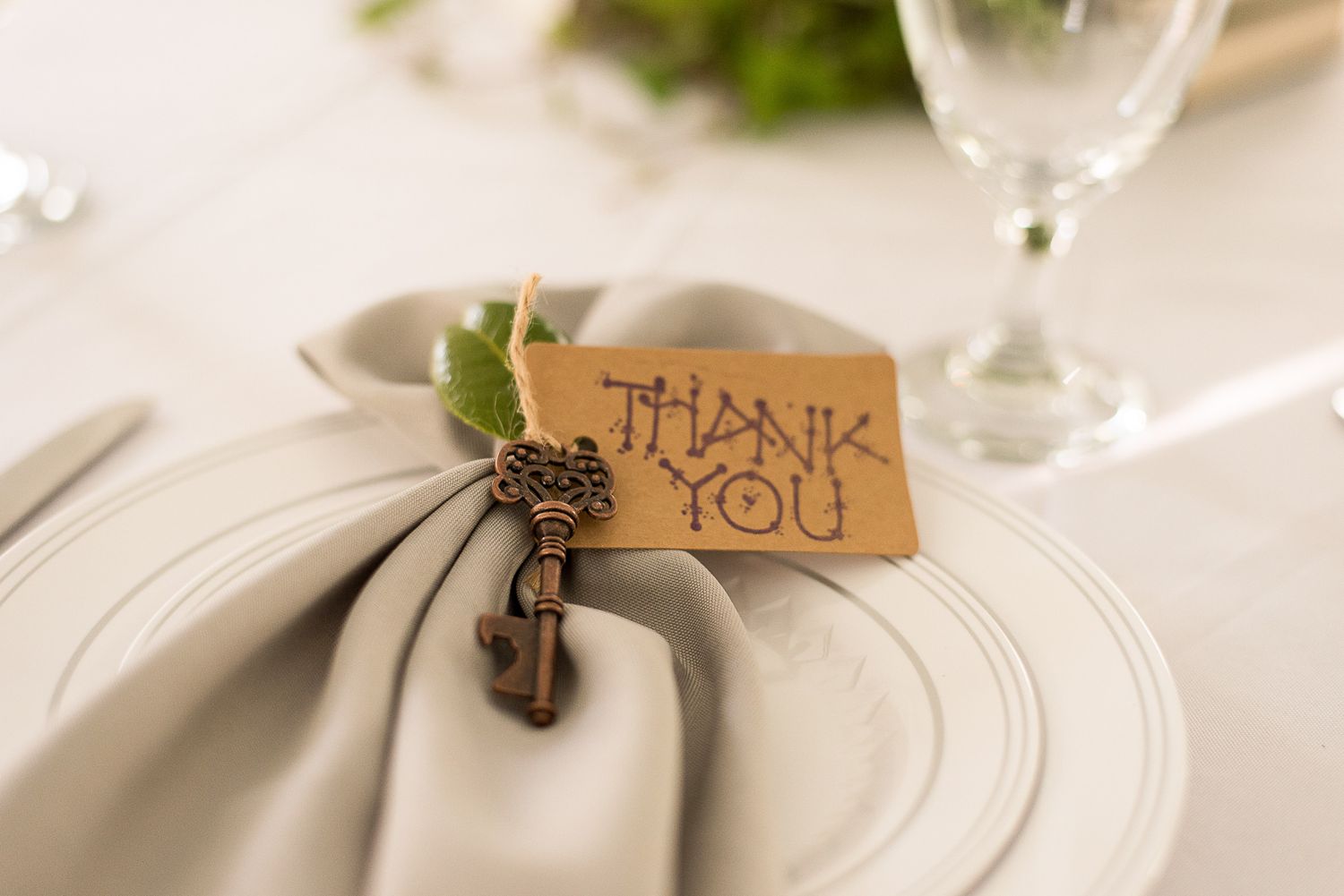 Wedding place settings with handwritten thank you notes attached to napkins.