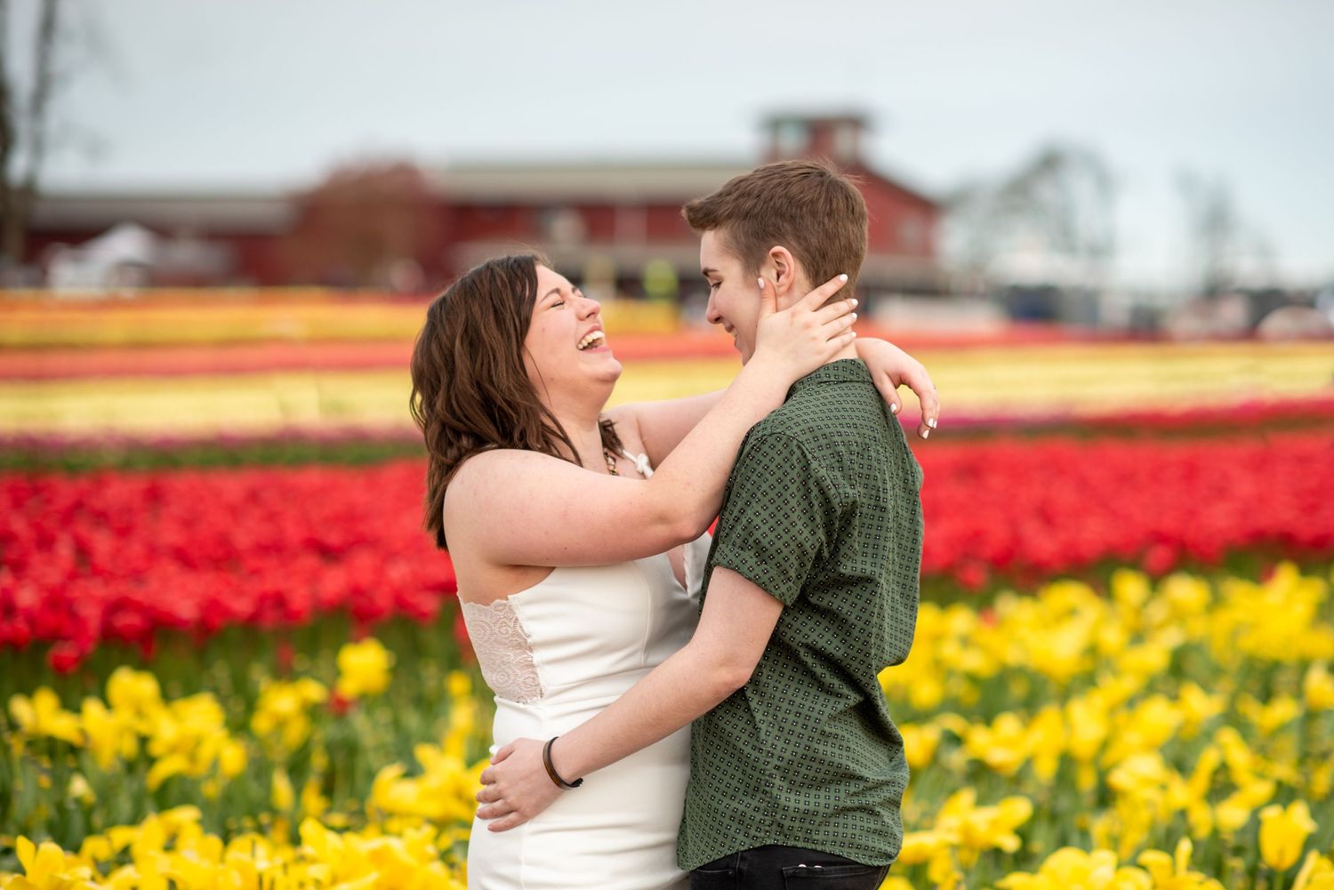Couple poses lovingly in front of colorful tulip fields during spring.