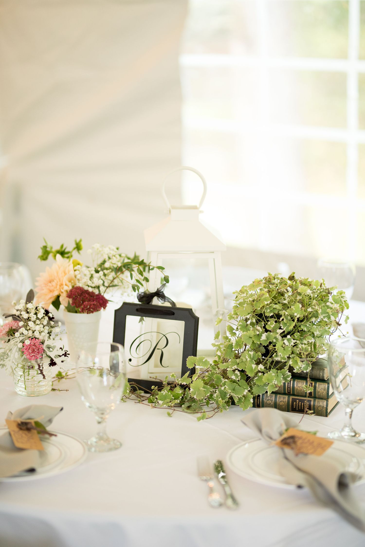 Elegant wedding table settings with greenery centerpieces and white linens in natural light.