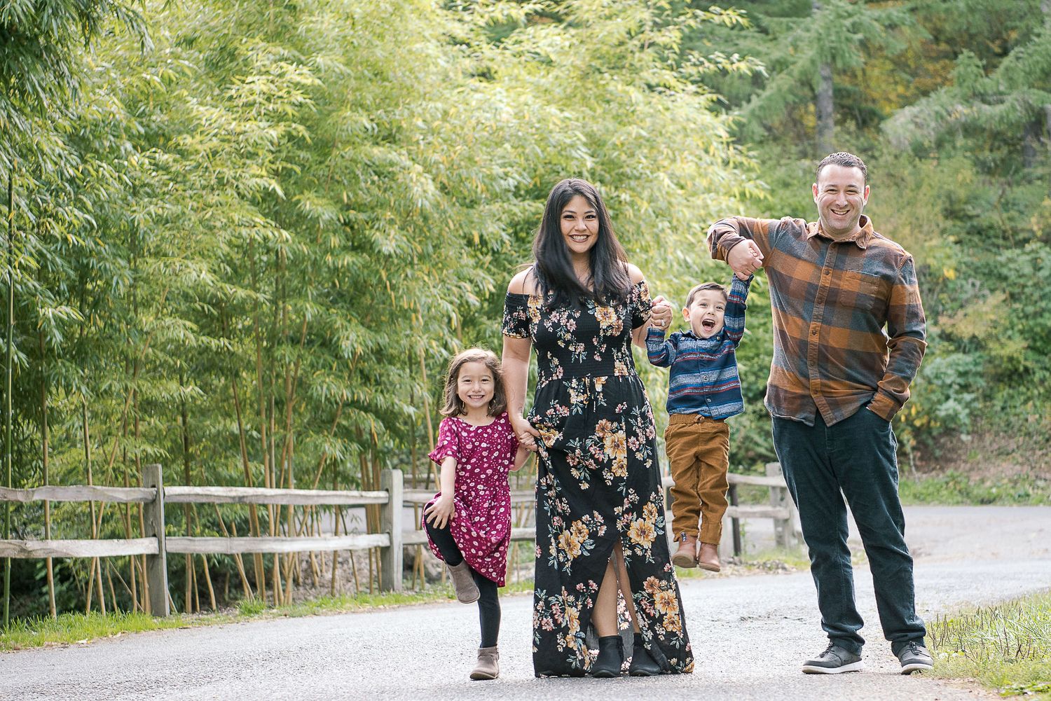 Family members walk together on a path surrounded by tall trees and greenery.