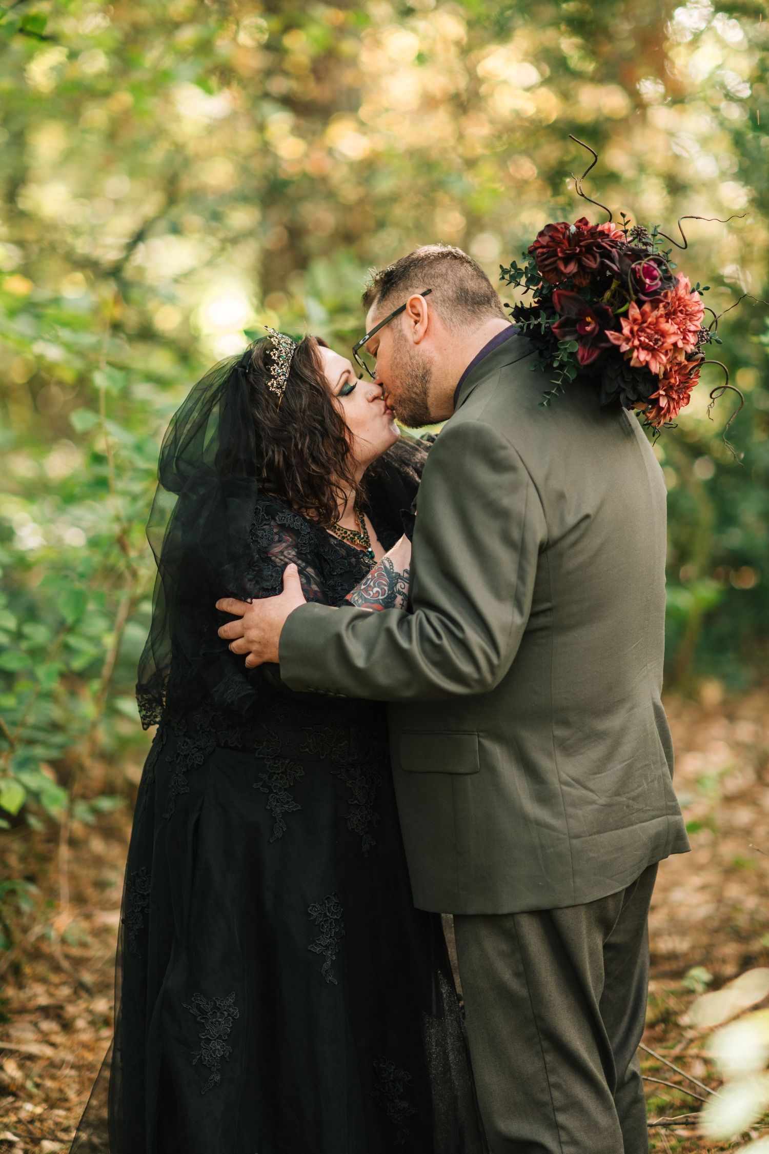 A romantic woodland photoshoot featuring a couple in black and gray attire among fall foliage.