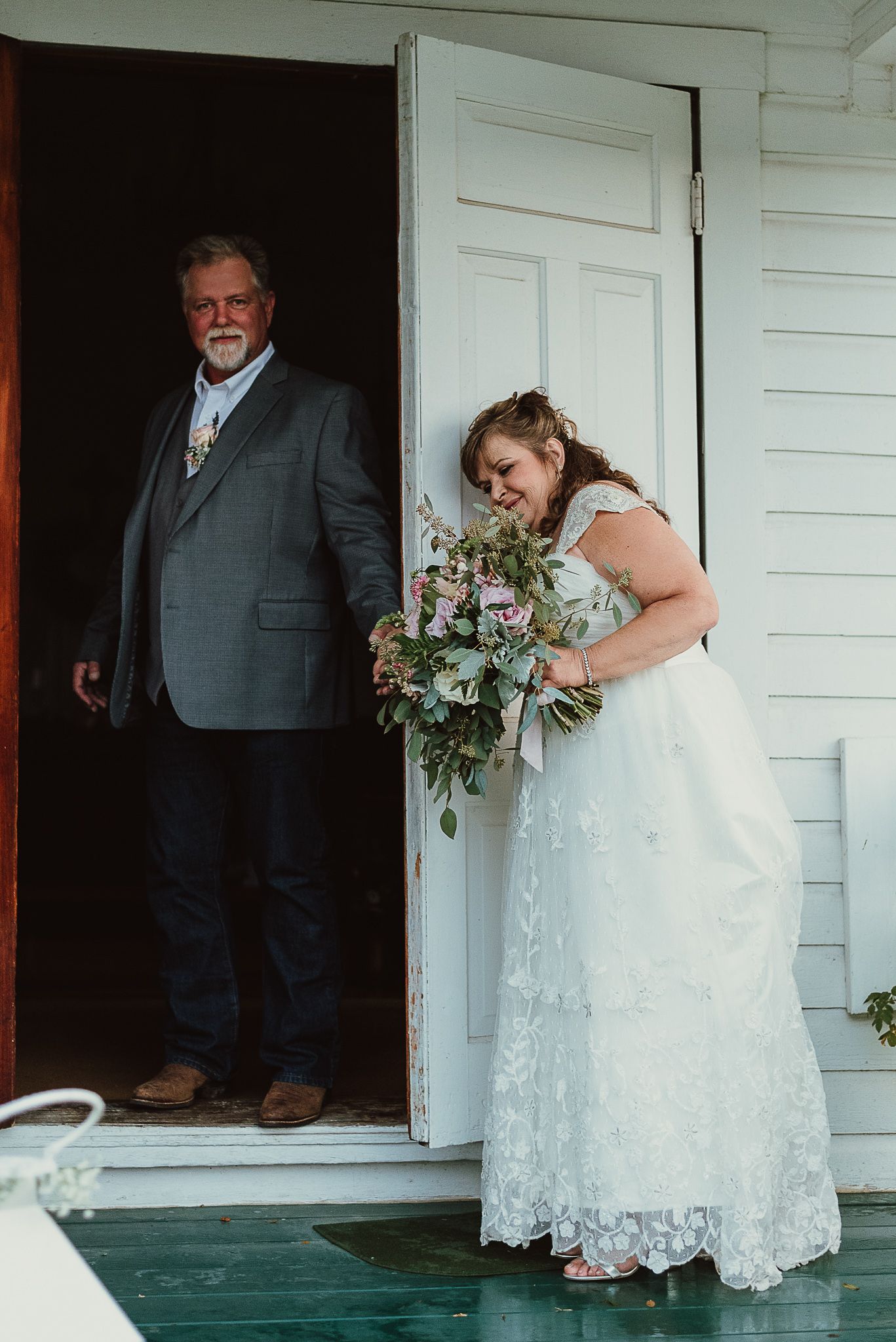 A wedding party standing on the porch of a white historic building.