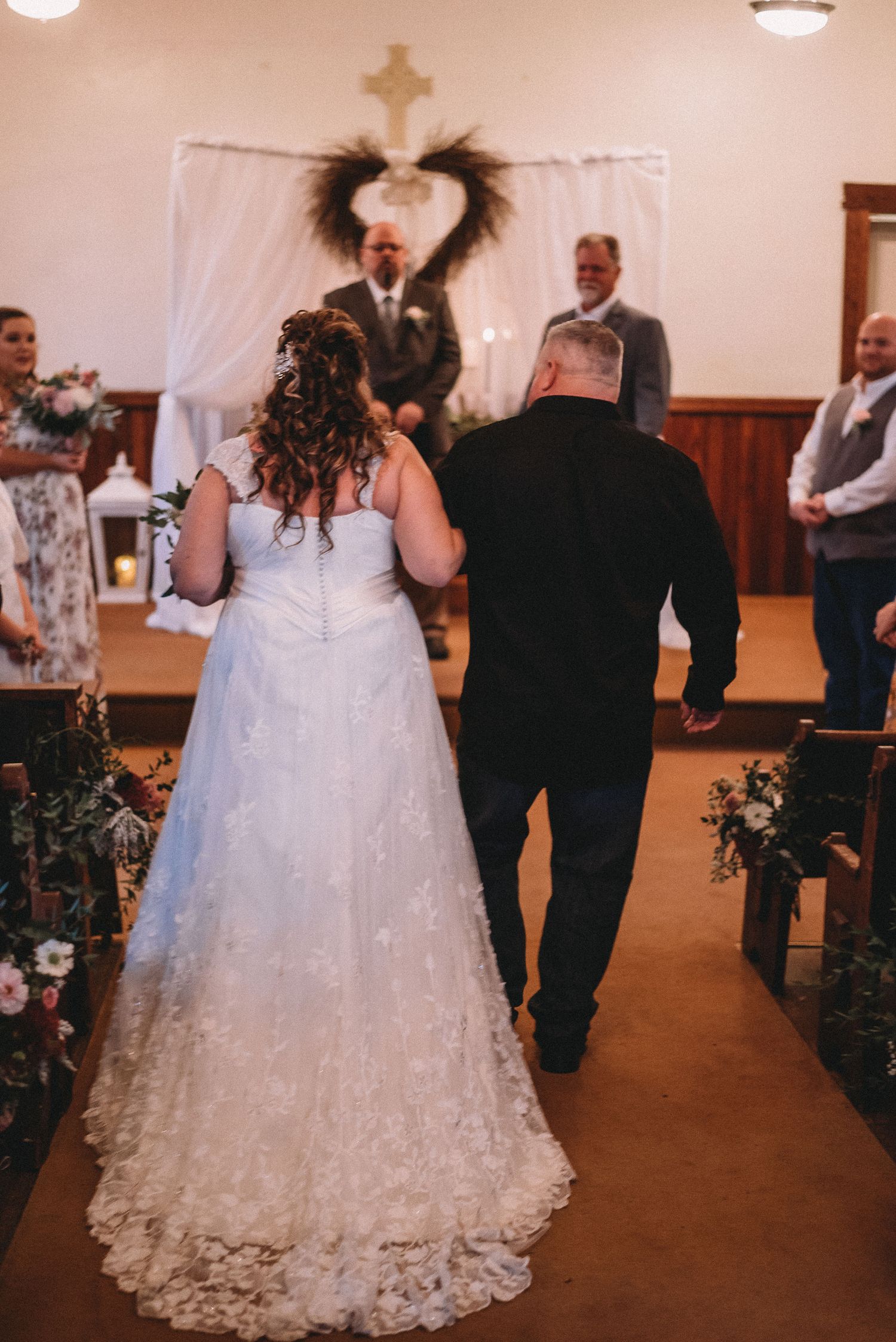 A wedding ceremony in progress inside a church with decorative floral arrangements.