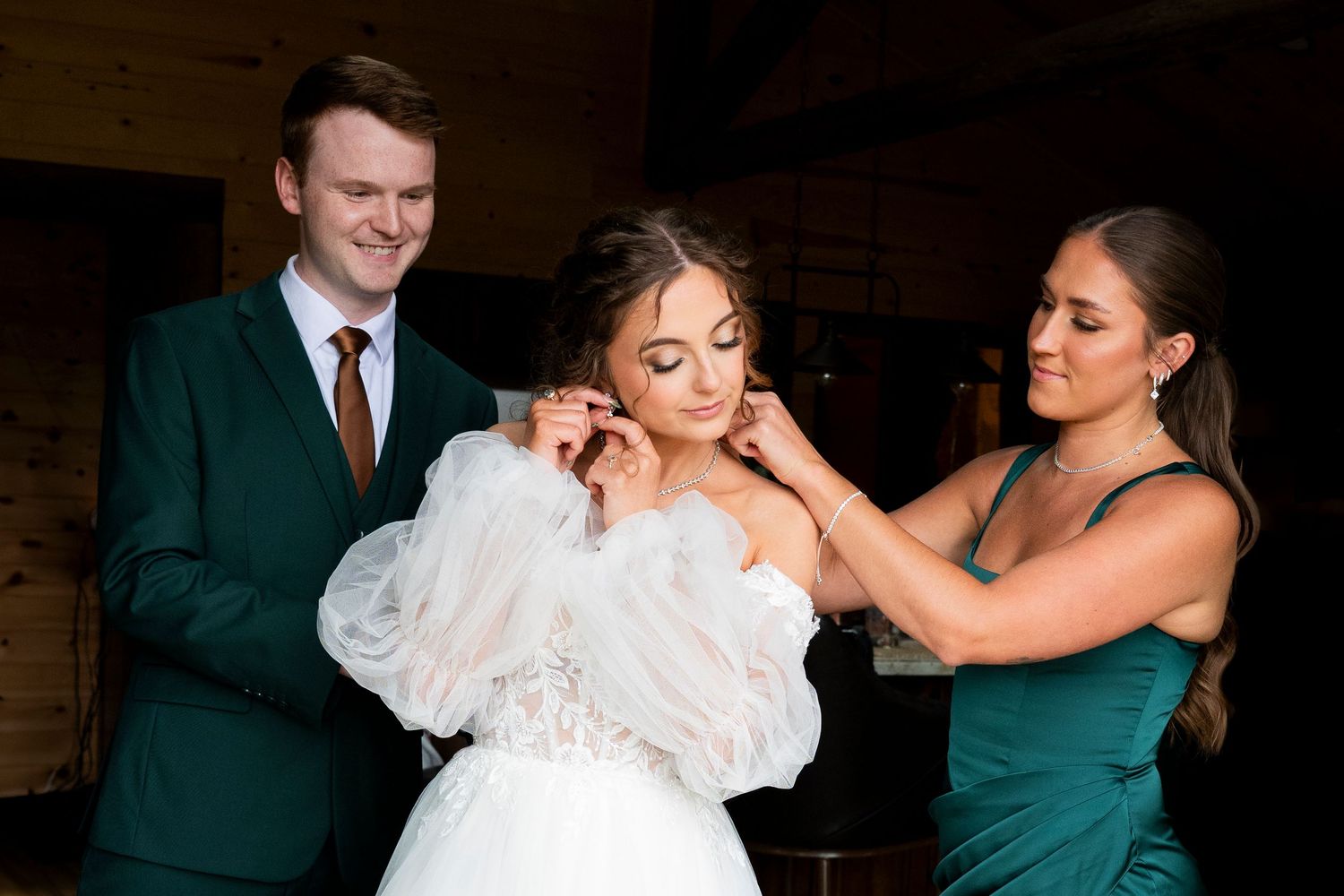 A brides man and bridesmaid help the bride get ready before her oregon wedding ceremony