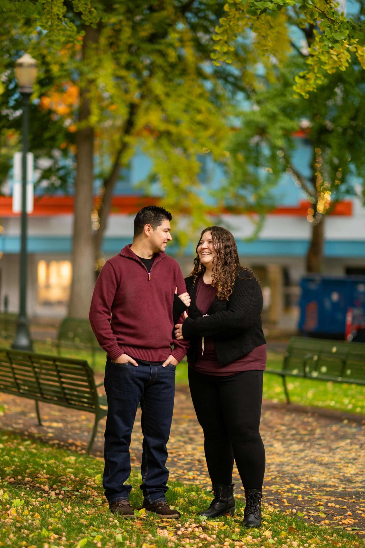 Couple sharing a sweet moment together in a colorful autumn park during their fall engagement session.
