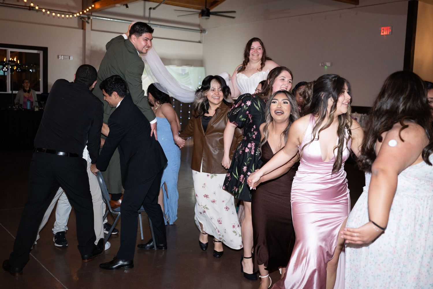 Guests dancing and celebrating at a lively wedding reception on a dance floor.