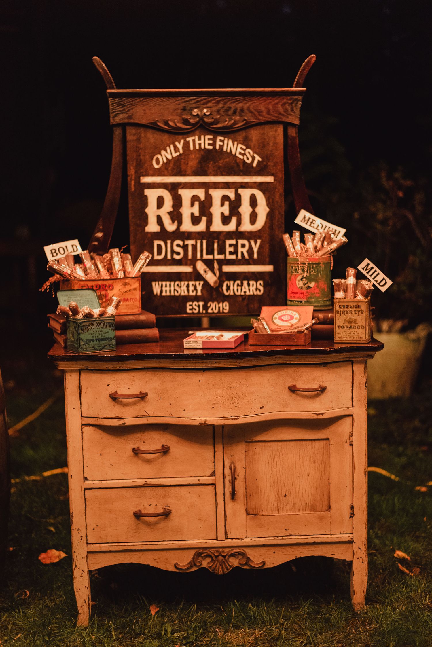 A vintage dresser decorated as a Reed Distillery whiskey and cigar station.