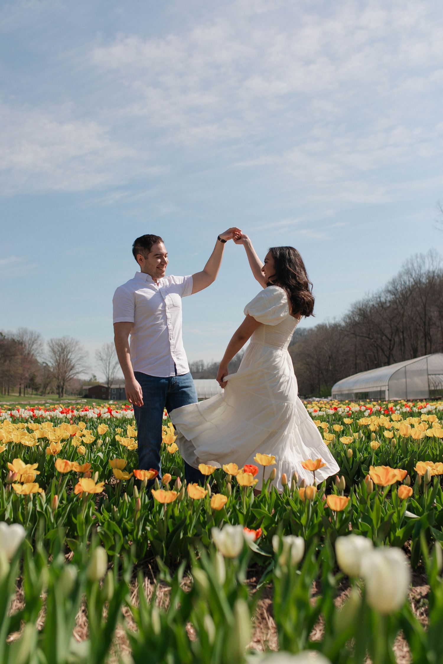 Nashville couple dancing together in a colorful tulip field on a sunny spring day.