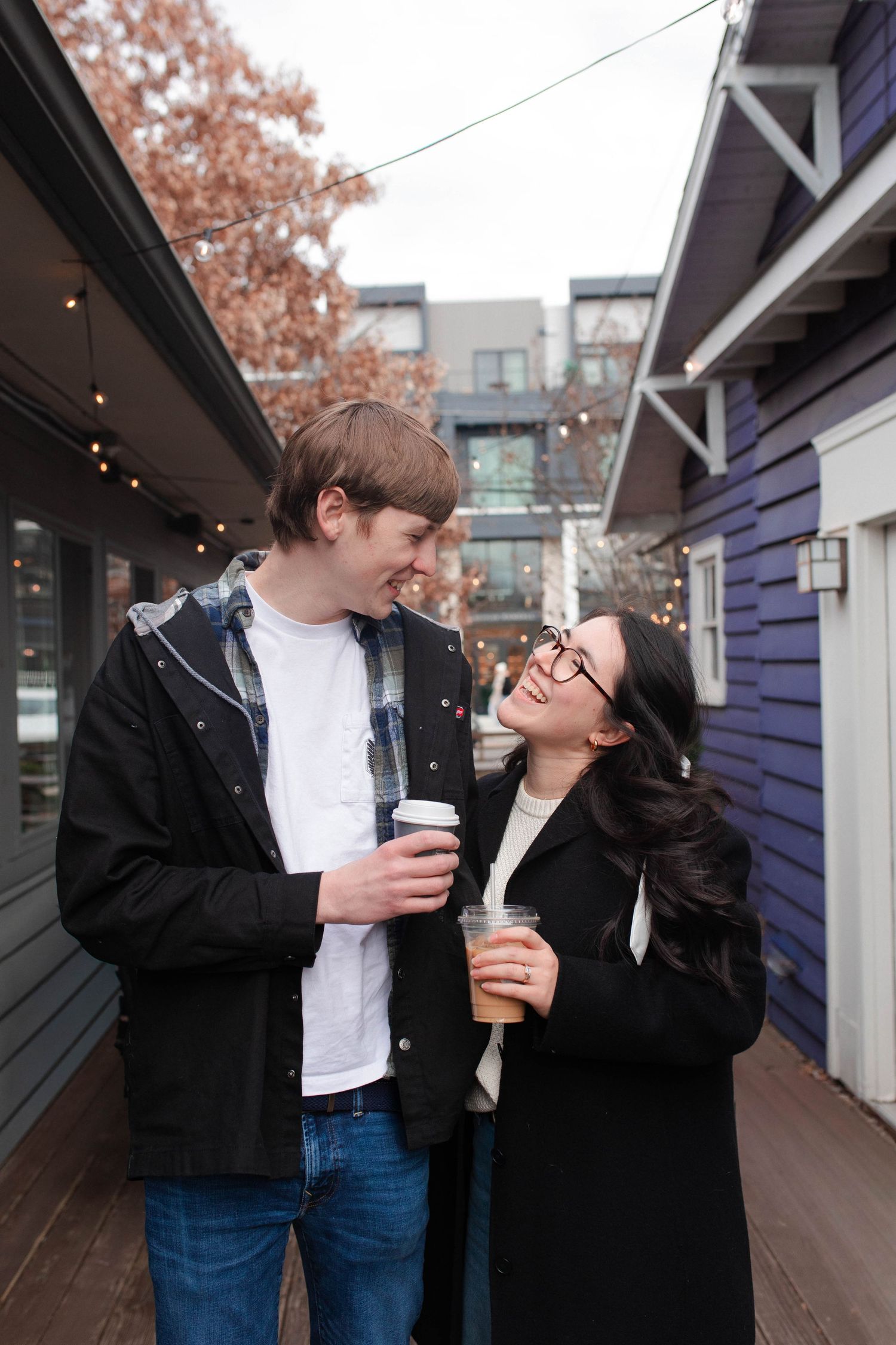 Happy couple holding coffee cups and smiling at each other on an outdoor patio at Frothy Monkey in East Nashville.