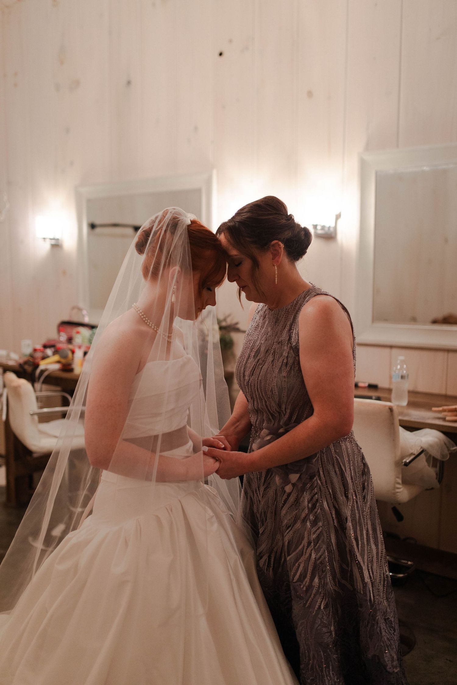 Bride in white gown and veil shares an intimate forehead touch moment with woman in silver dress before micro wedding in Nashville.