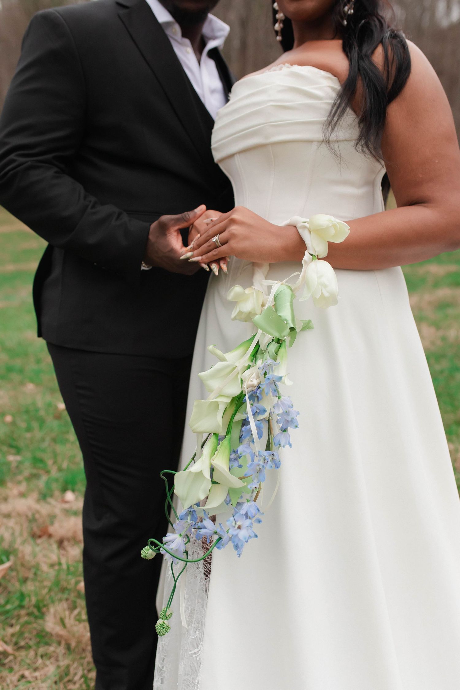 Bride and groom holding hands, bride wearing white strapless gown with cascading white and blue floral bouquet after eloping in Nashville.