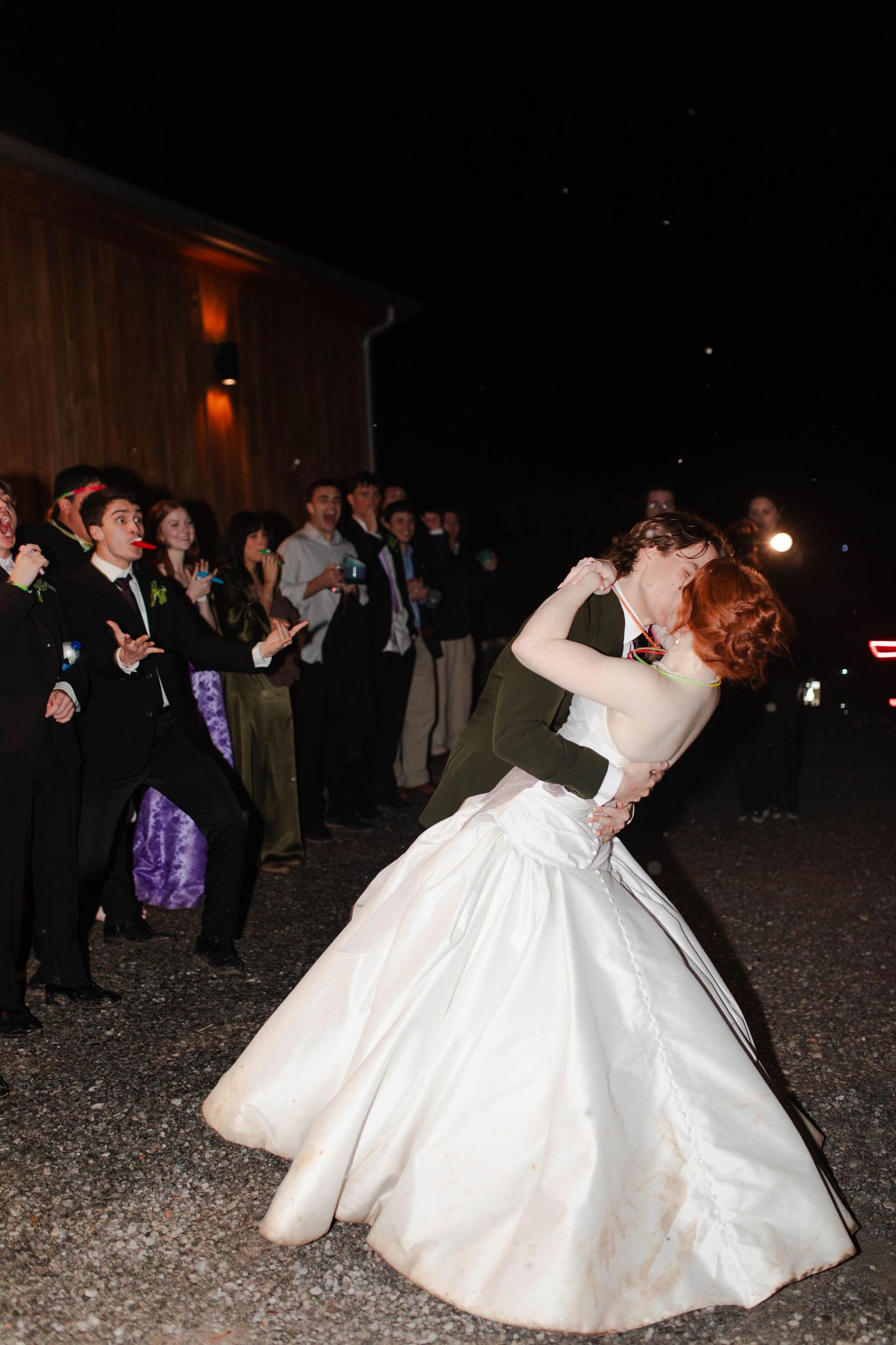Groom dipping bride in white gown at outdoor evening wedding reception in Nashville.
