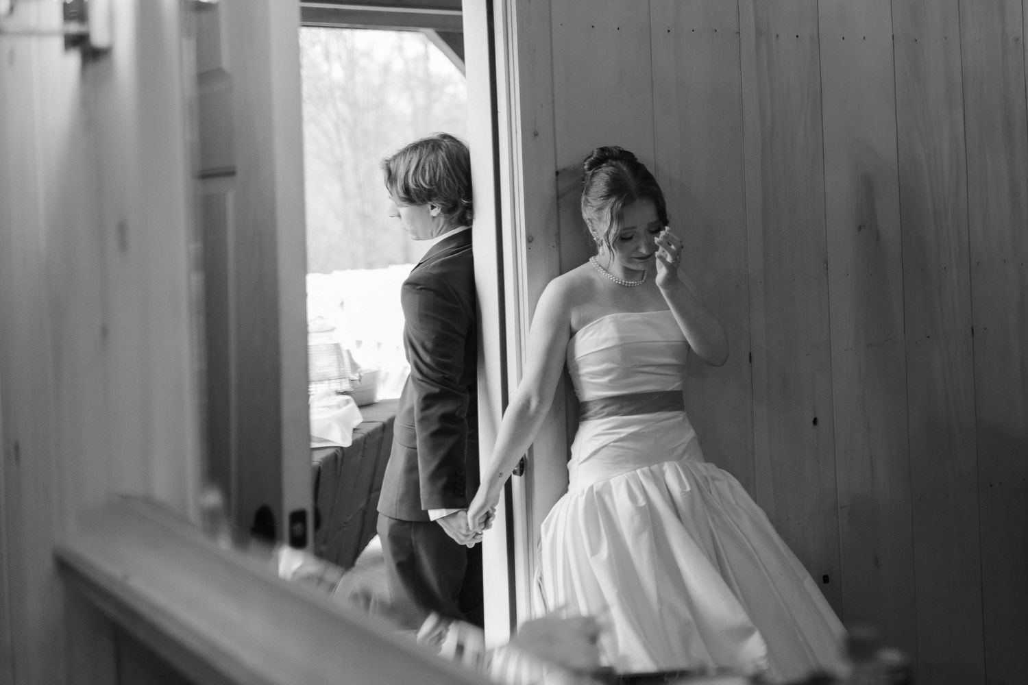Black and white photo of bride and groom holding hands through barn doorway after eloping in Nashville.