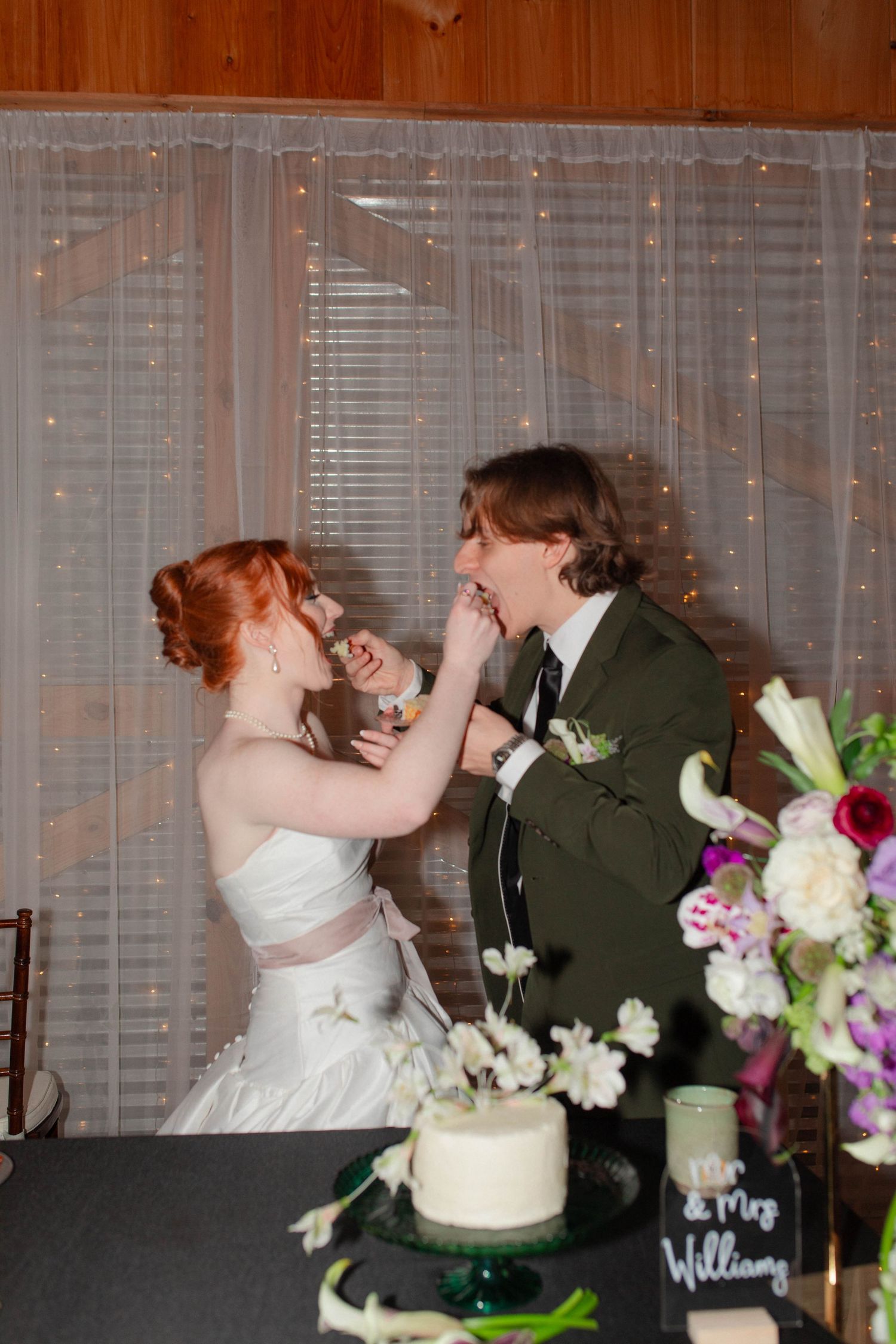 Bride feeding wedding cake to laughing groom at initmate reception venue after eloping in Nashville.
