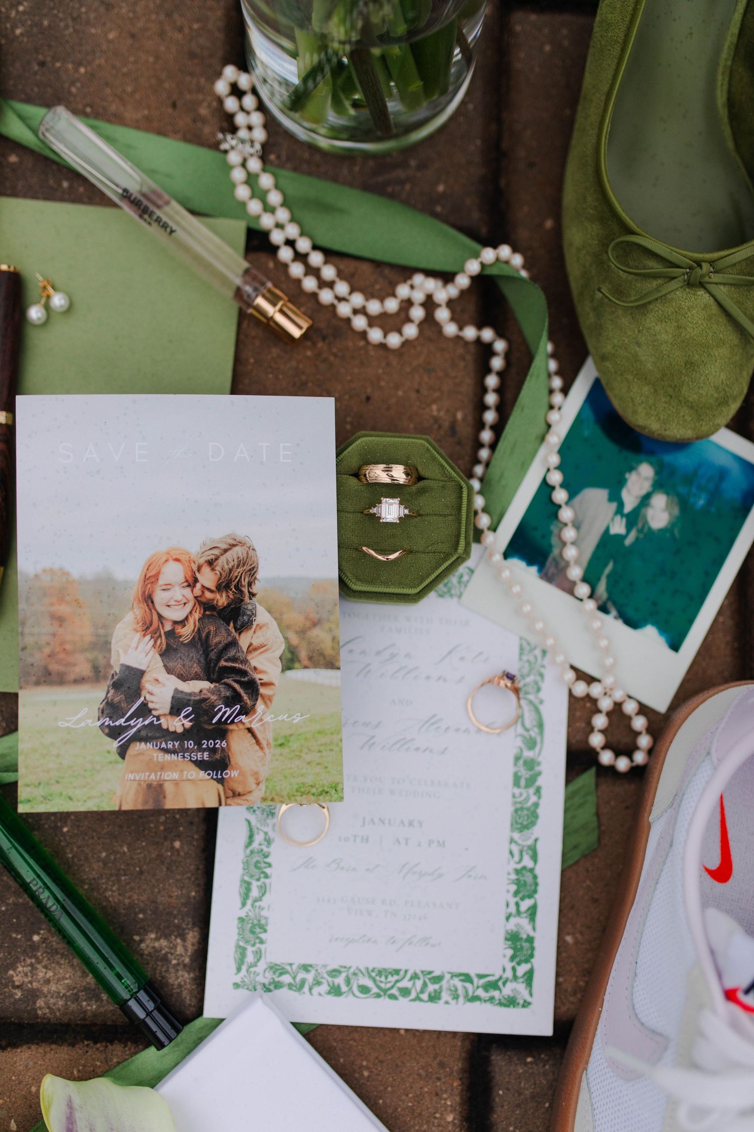 Nashville micro wedding flat lay featuring save the date cards, rings, pearl necklace, green shoes, and gold jewelry.
