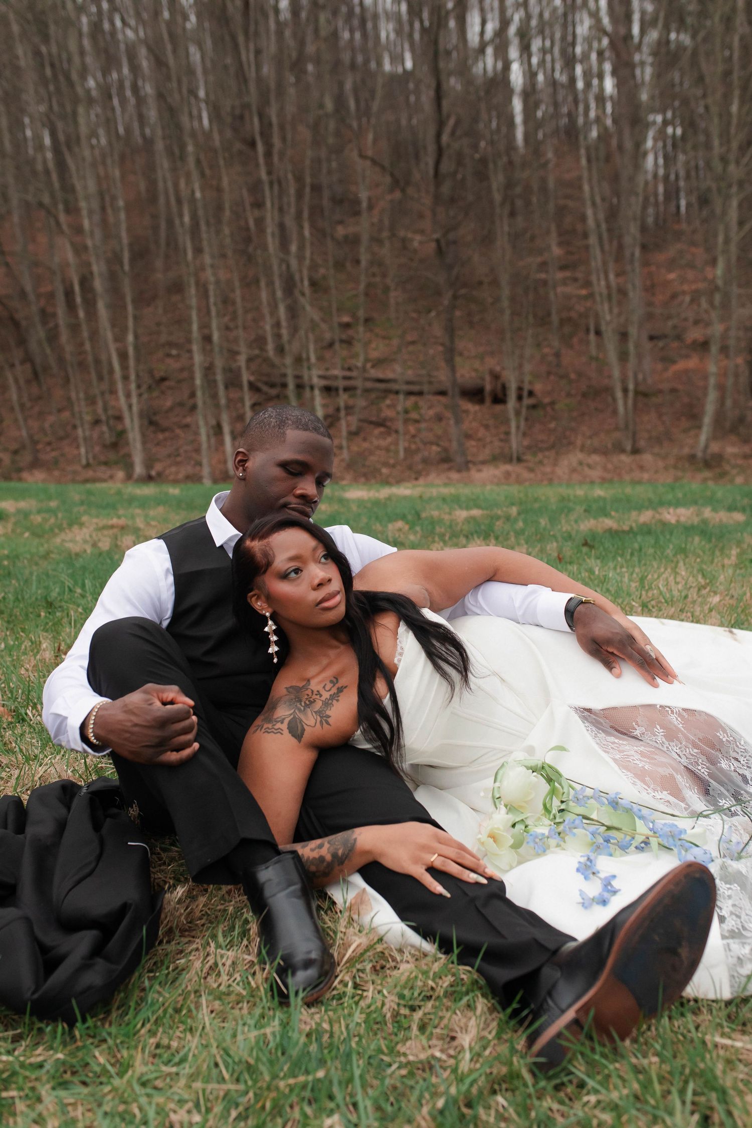 African American bride and groom relaxing together on grass in wooded setting after eloping in Nashville.