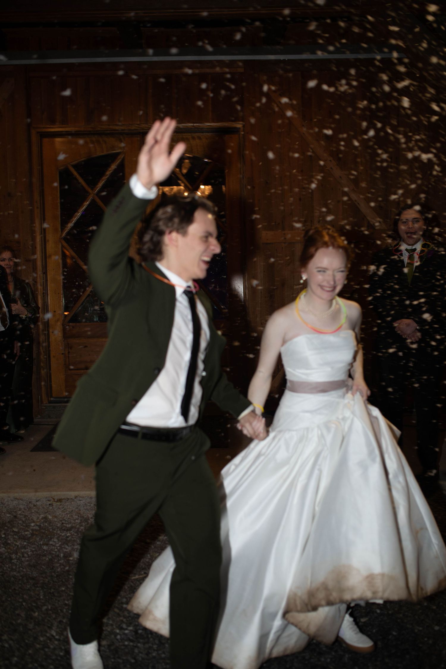 Bride and groom exit venue joyfully through confetti shower, groom in olive suit, bride in white gown after their micro weddin in Nashville.