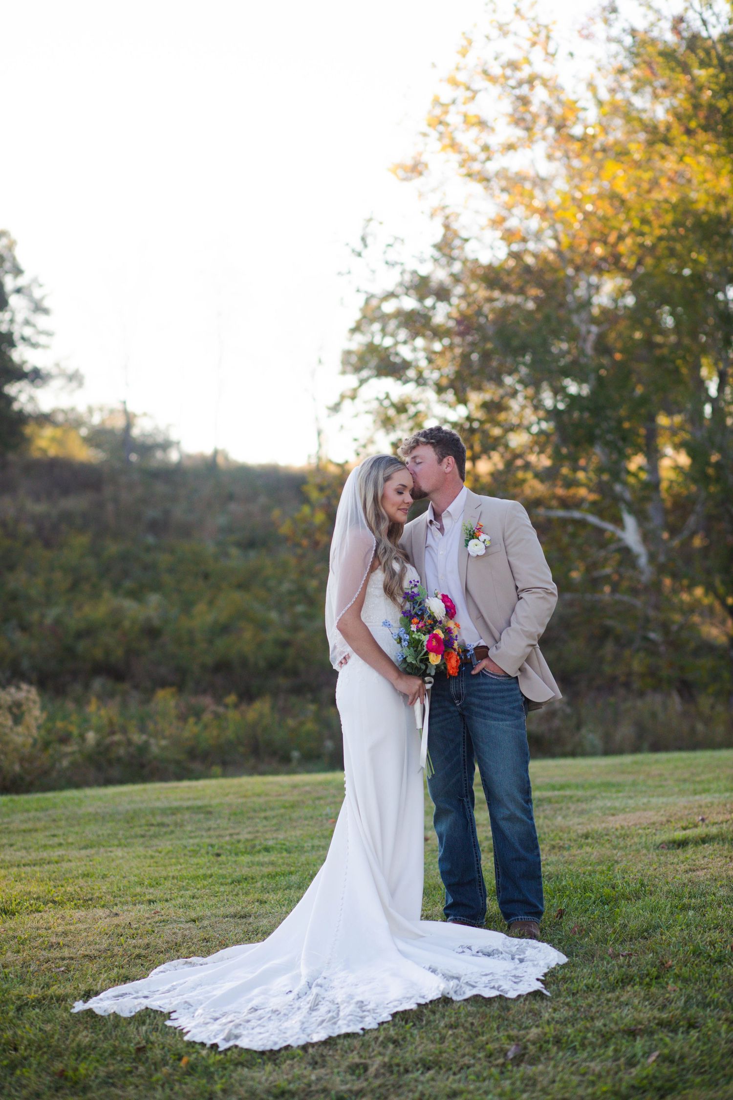 Bride in lace wedding gown and groom in tan blazer and jeans share a tender moment at sunset after eloping in Nashville.