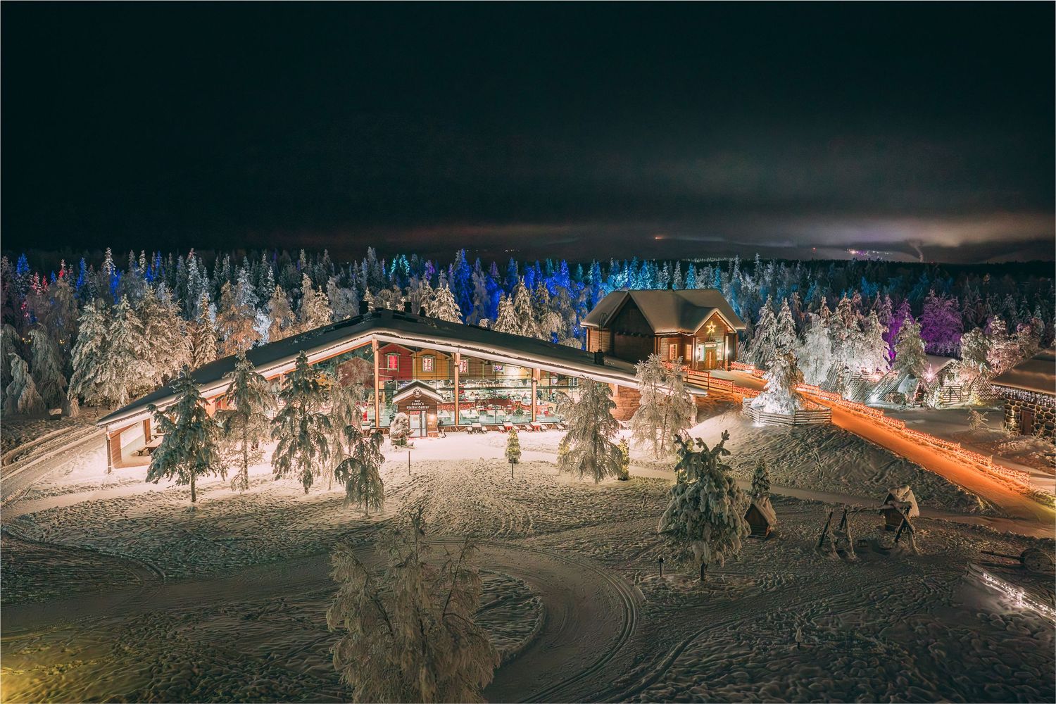 Illuminated Lapland lodge and snow-covered pine trees glowing warmly against a dark winter night sky.