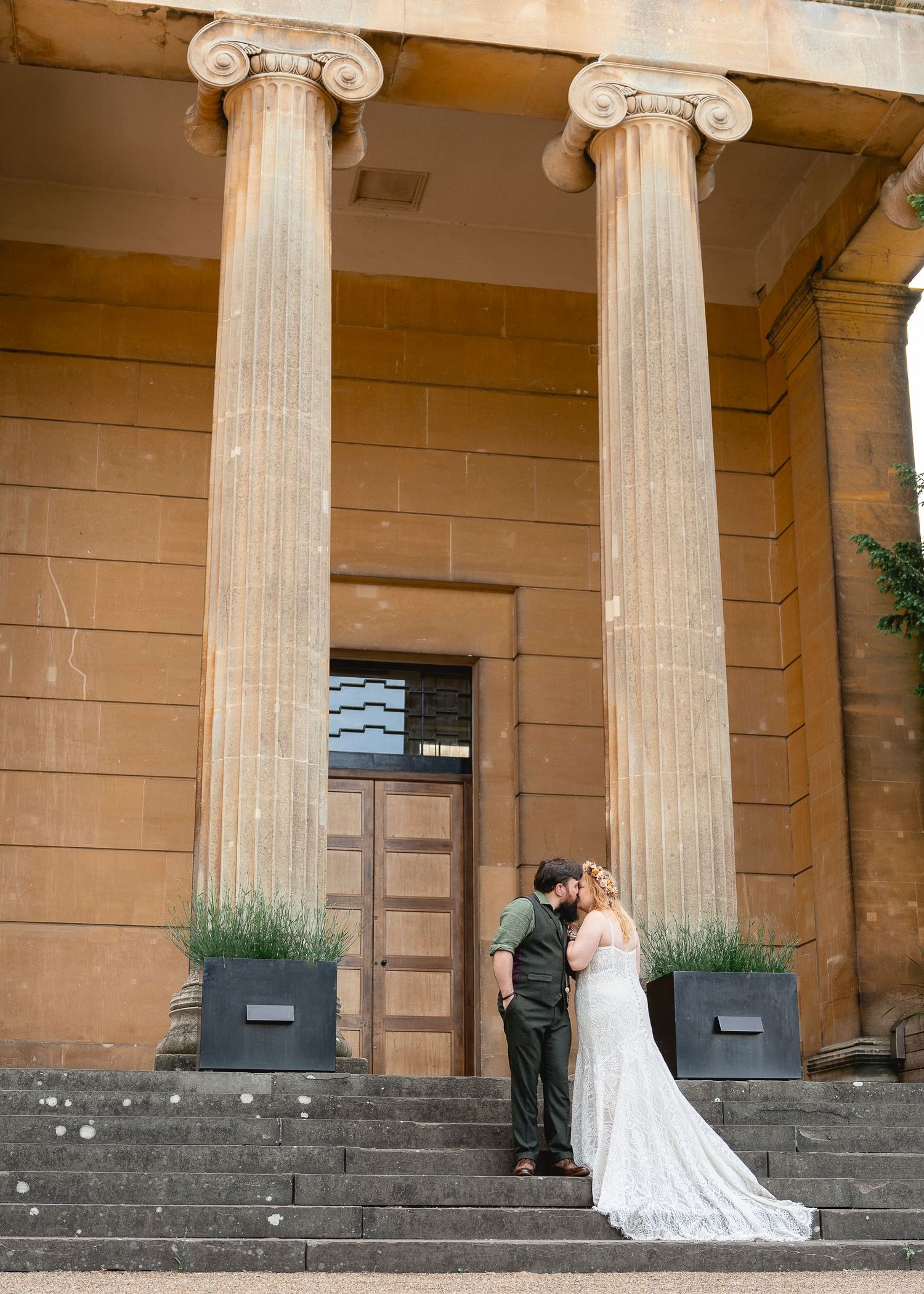 Wedding photos on classical stone steps with Ionic columns in the background.