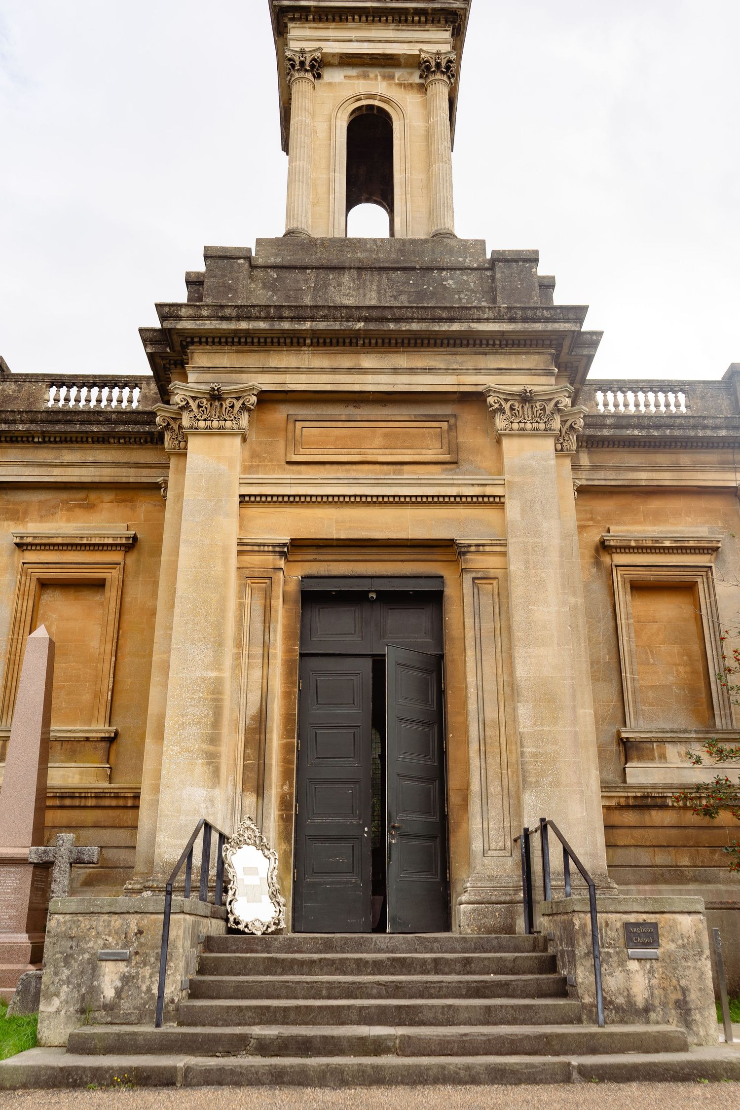 Neoclassical stone church exterior with grand entrance steps, ornate columns, and bell tower under overcast sky.