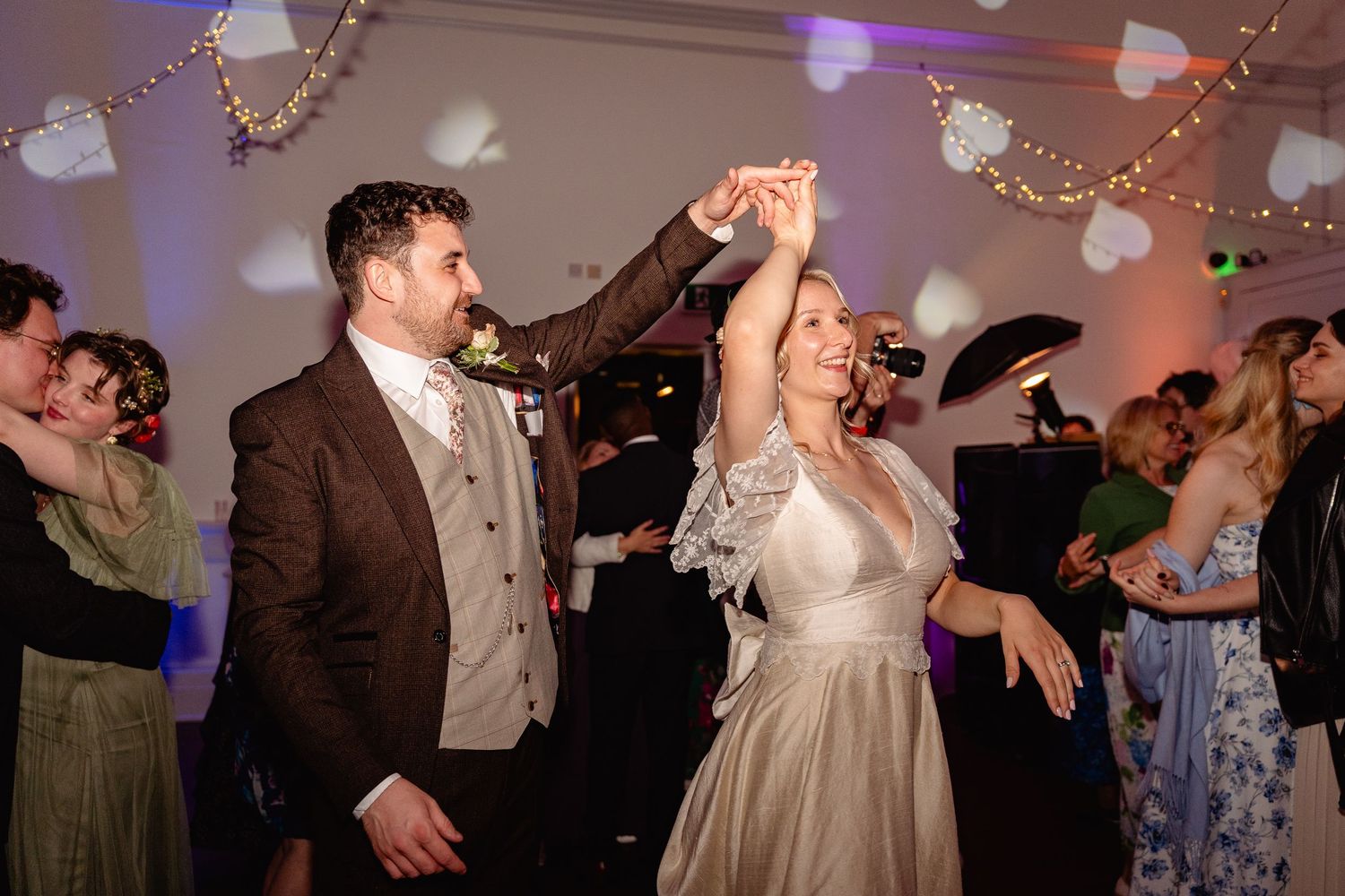 Bride and groom share a joyful first dance at their wedding reception, surrounded by guests and festive decorations.