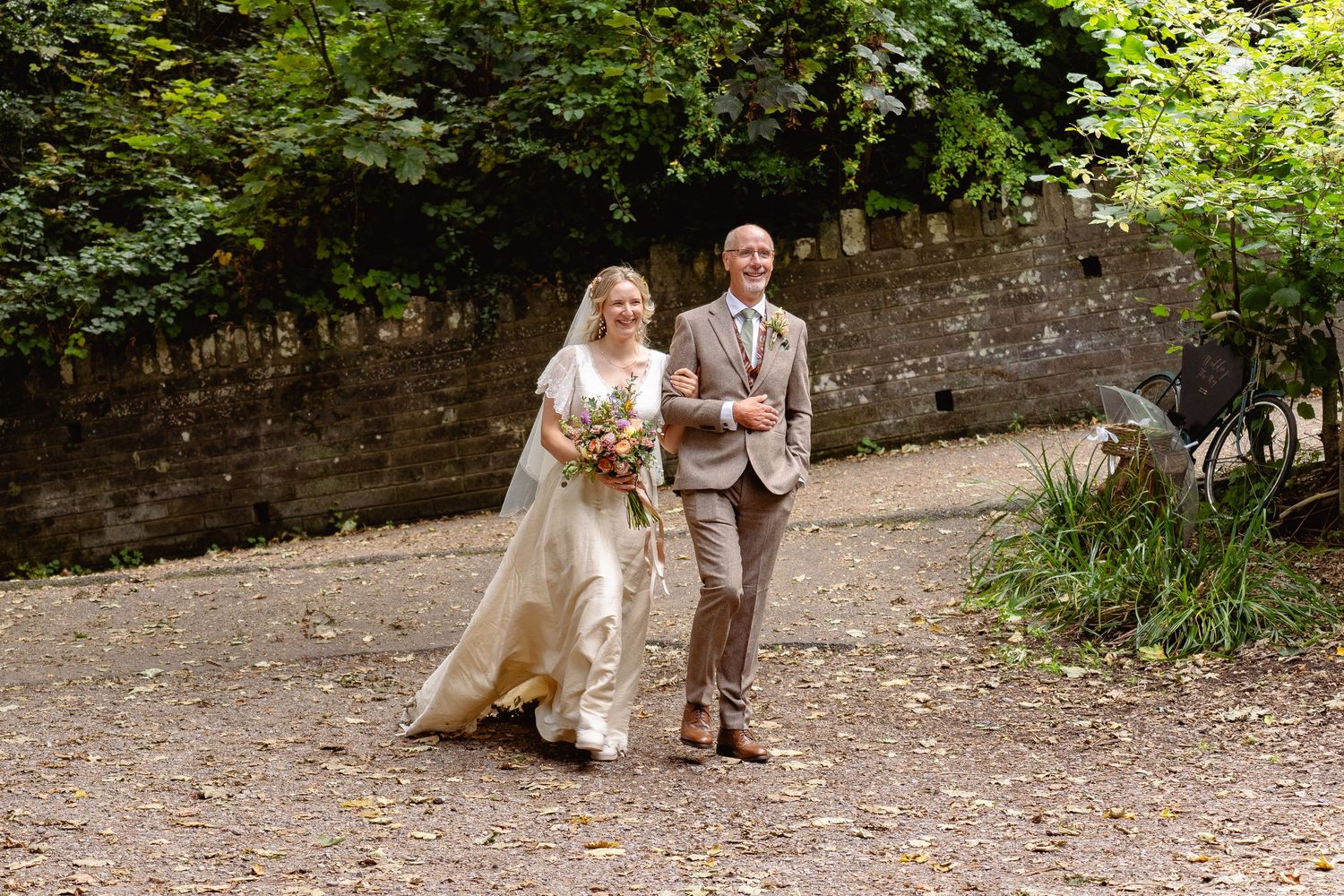 Bride and groom walking hand in hand through a lush garden path on their wedding day.