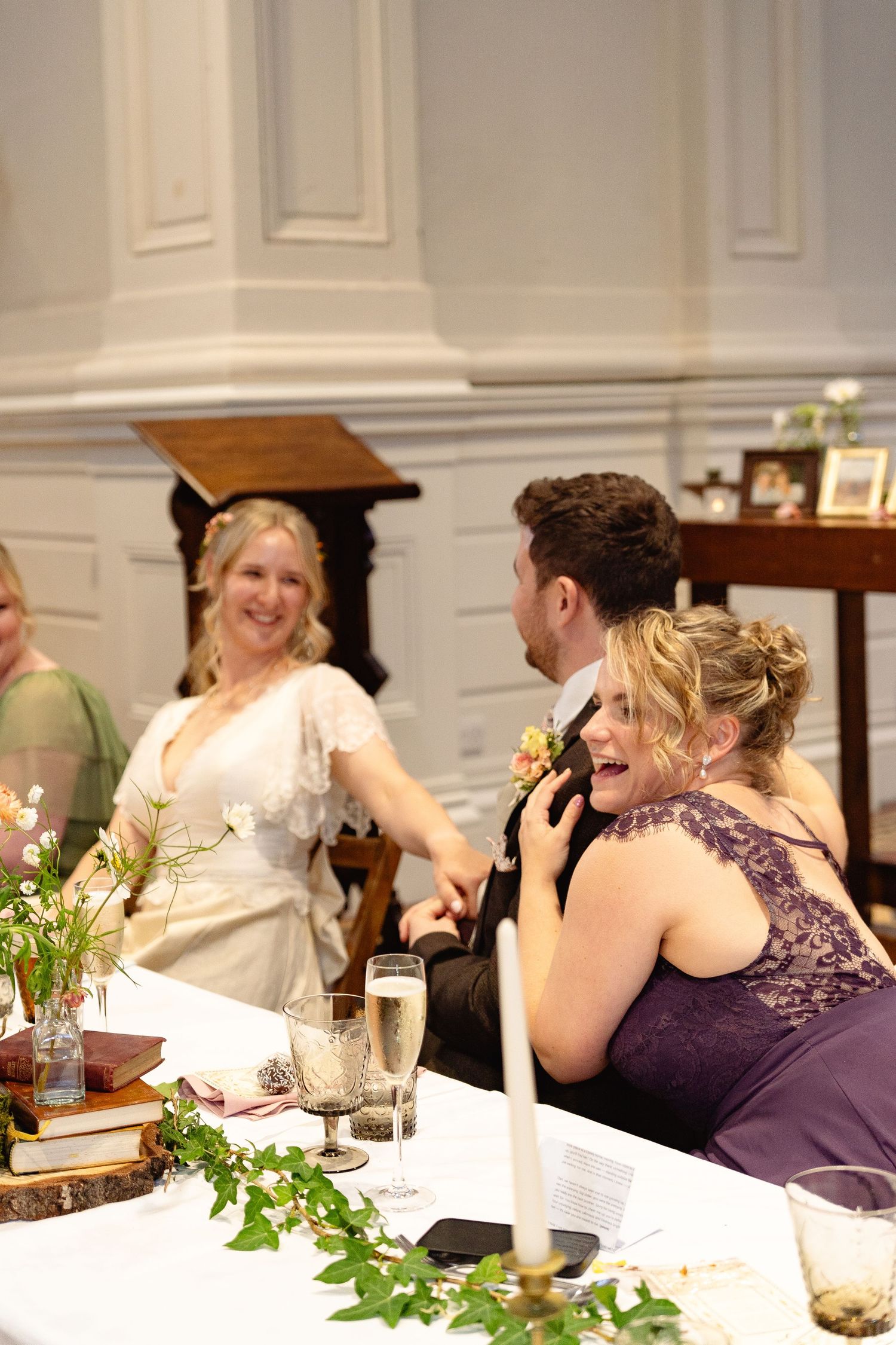 Bride and wedding guests laughing and celebrating together at a elegant wedding reception dinner.