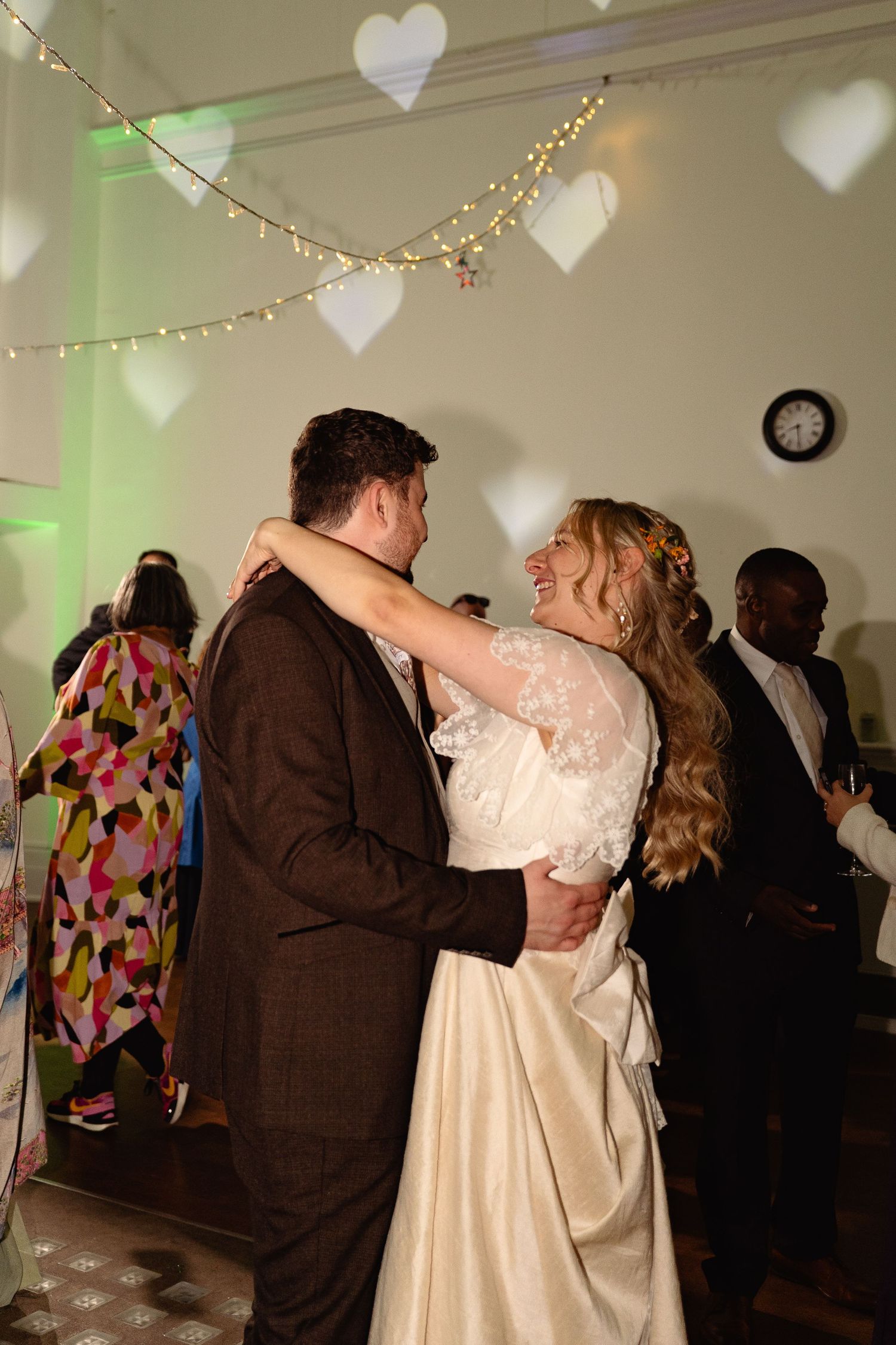 Bride and groom sharing their first dance under heart-shaped light projections.