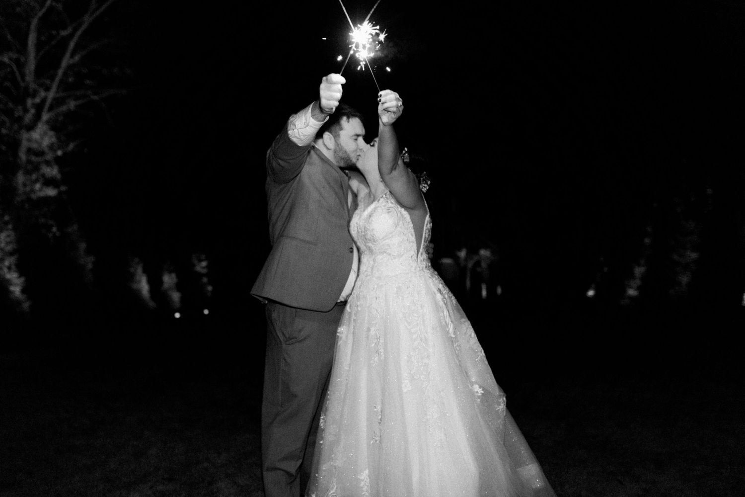 bride and groom hold sparklers and kiss