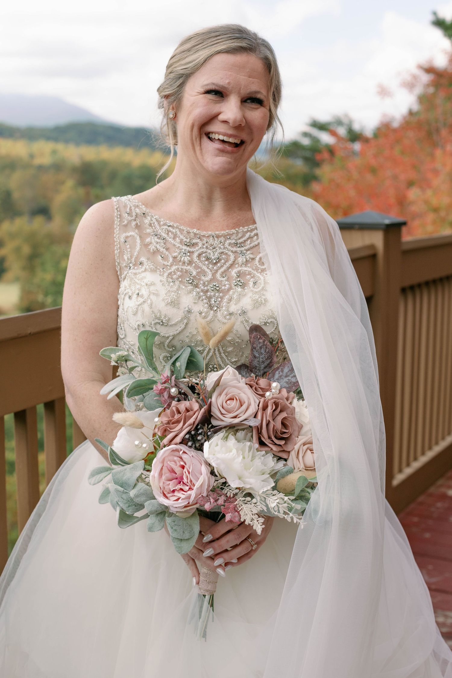 bride laughts playfully while holding bouquet and veil