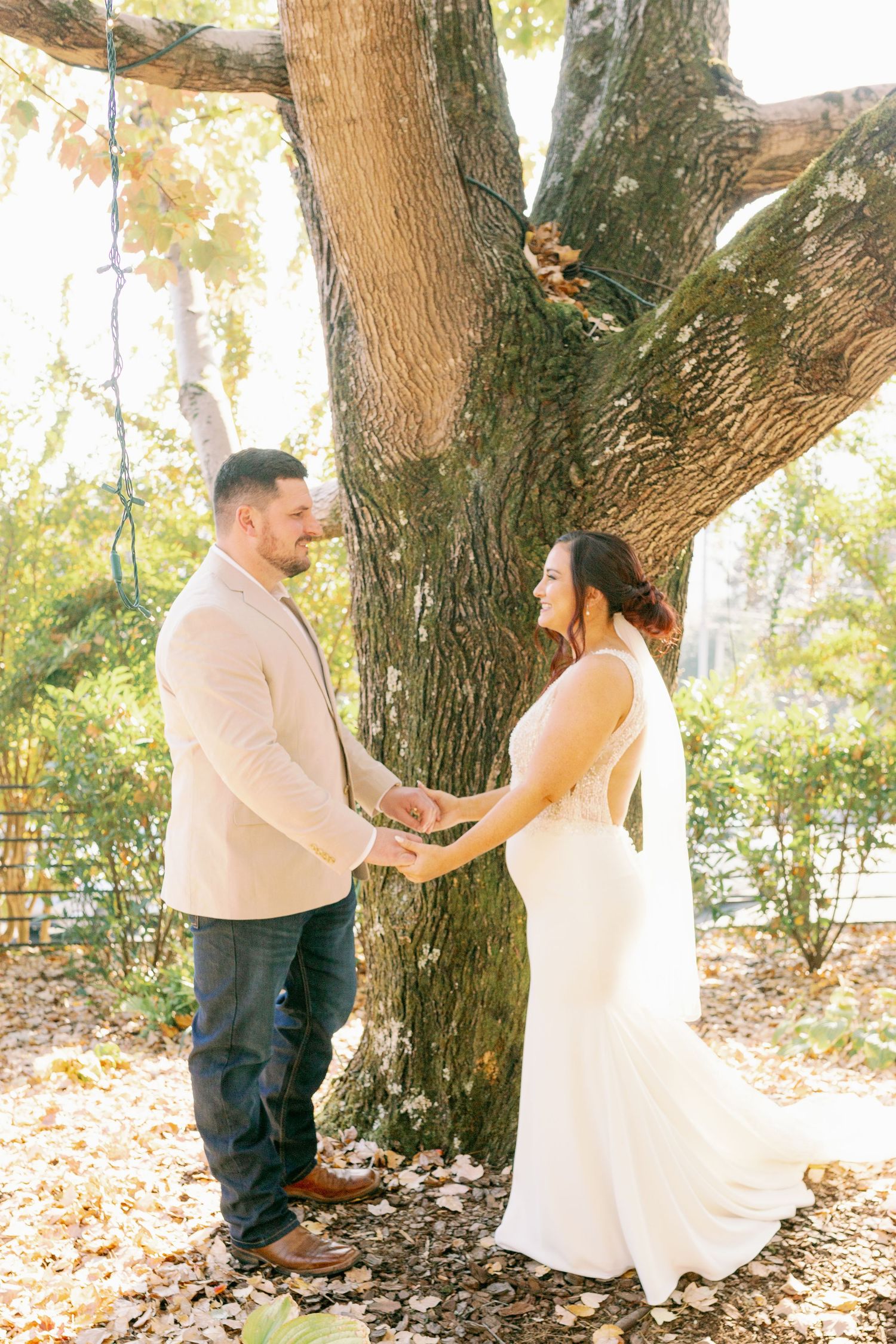 bride and groom hold hands in front of ceremony tree