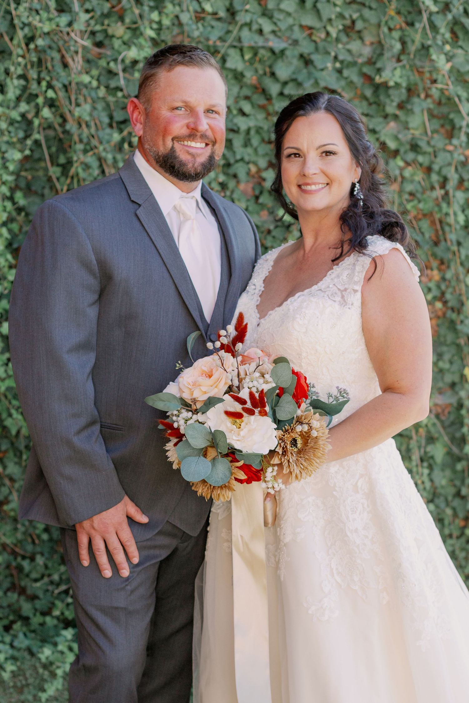 wedding photo of couple in front of greeery wall