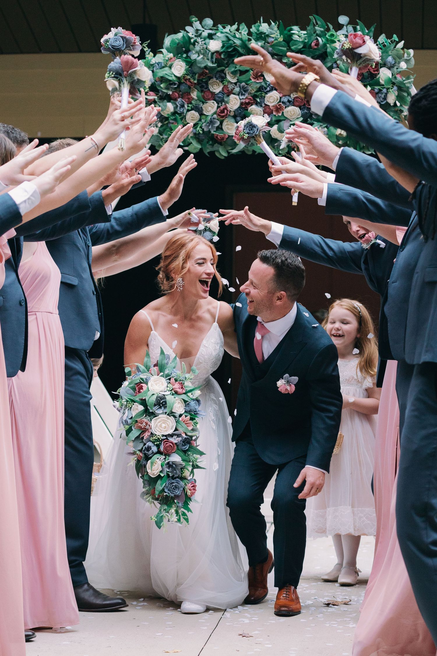 bride and groom walk through tunnel of friends and smile