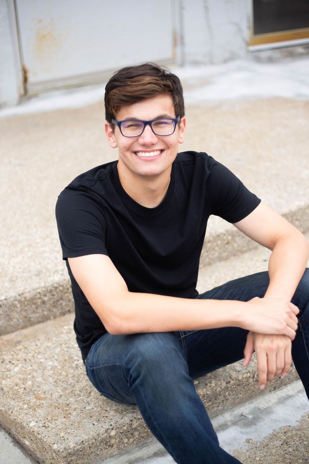 Casual portrait series on concrete steps featuring someone in black t-shirt and jeans. Mauston photographer.