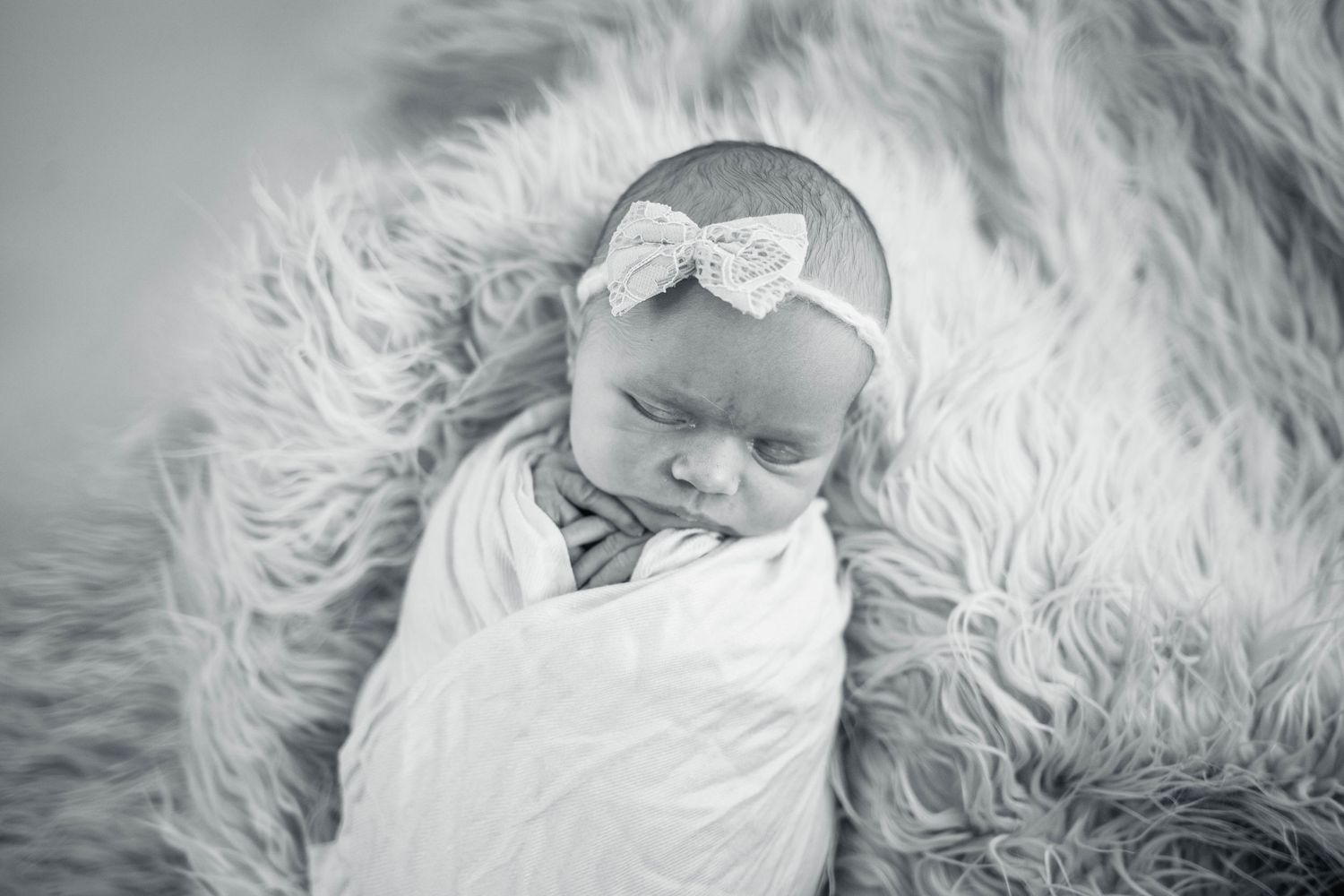 Peaceful sleeping newborn on white fluffy rug during professional photo session. Mauston photographer.