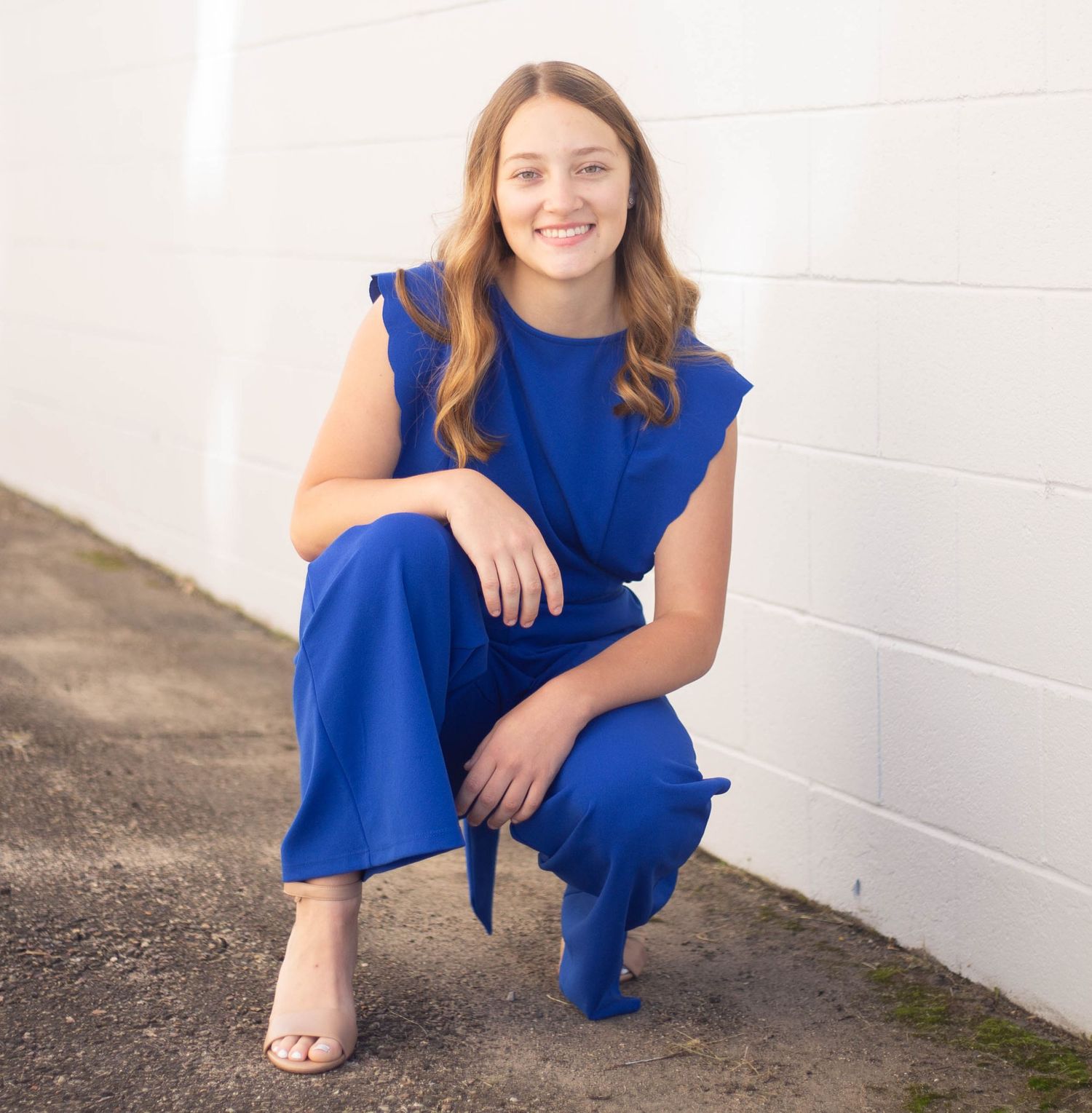 Fashion portraits against white wall wearing royal blue jumpsuit. Mauston photographer.