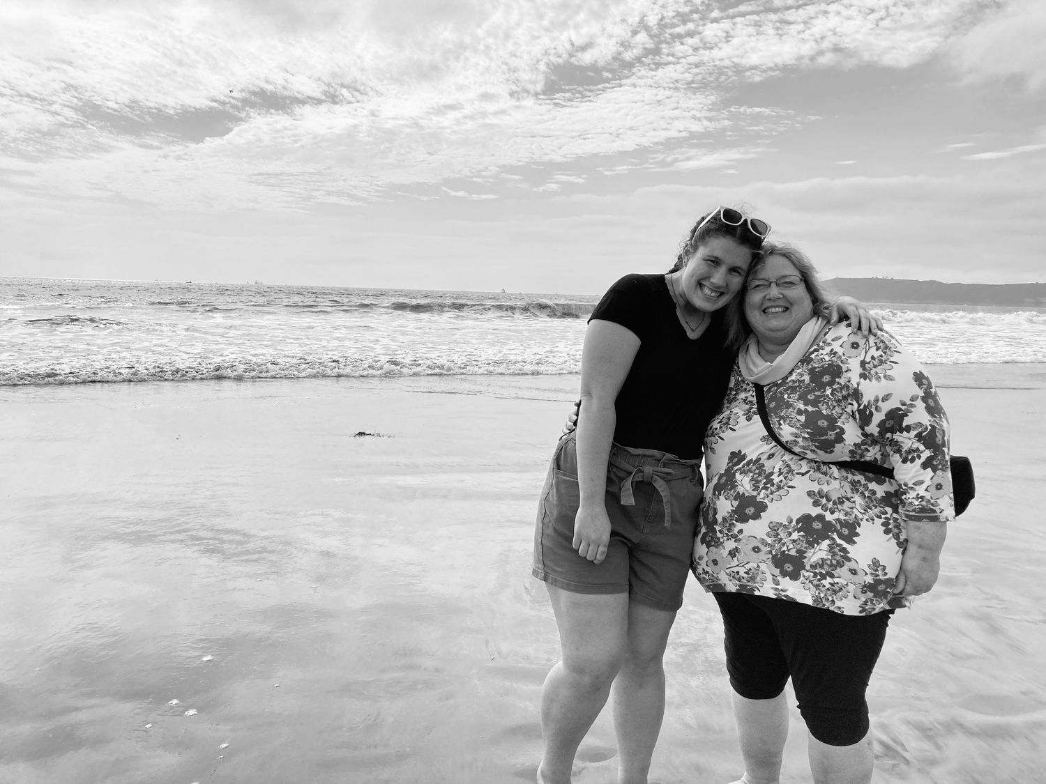 Group walking together along ocean shoreline in black and white. Mauston photographer.