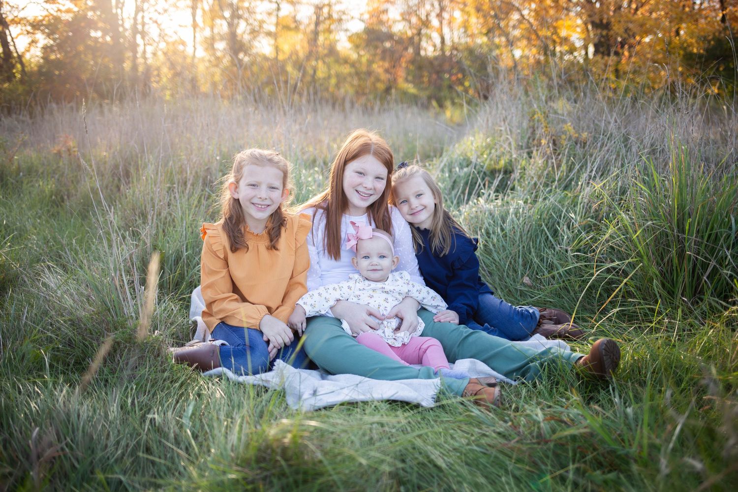 Family portrait in tall grass field during golden hour sunset. Mauston photographer.