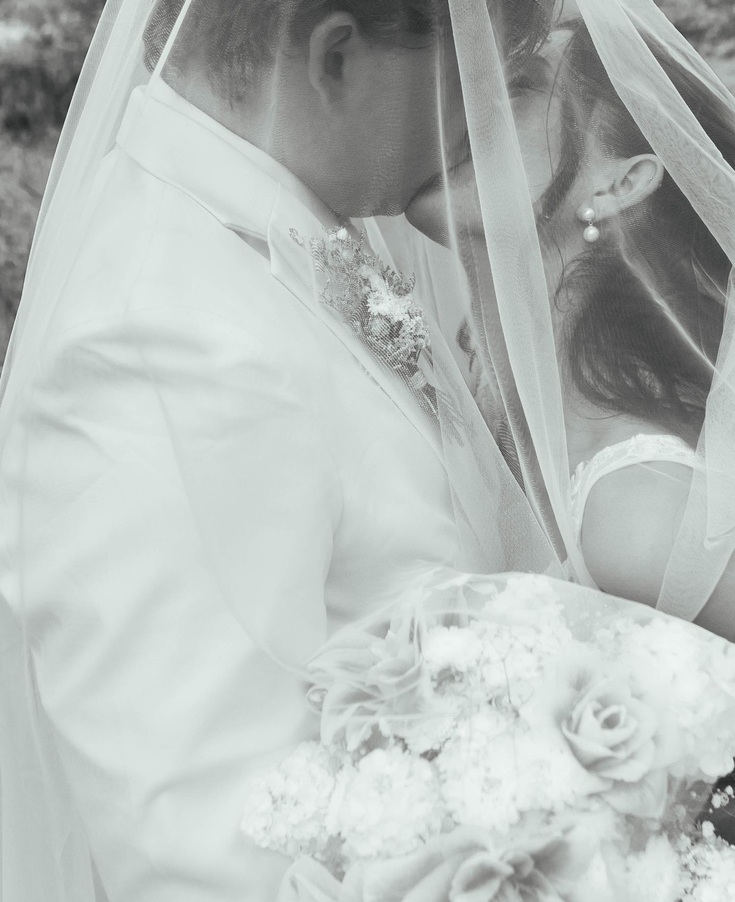 Close-up details of white wedding veil and bouquet in black and white photography. Mauston photographer.