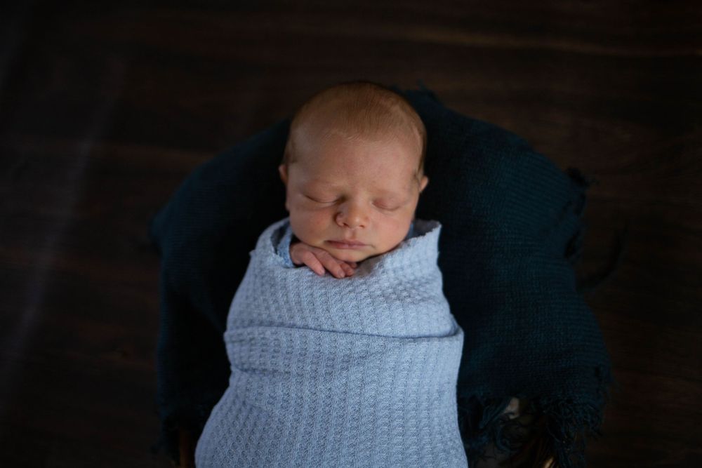 Professional newborn portrait with baby wrapped in soft blue knitted blanket. Mauston photographer.