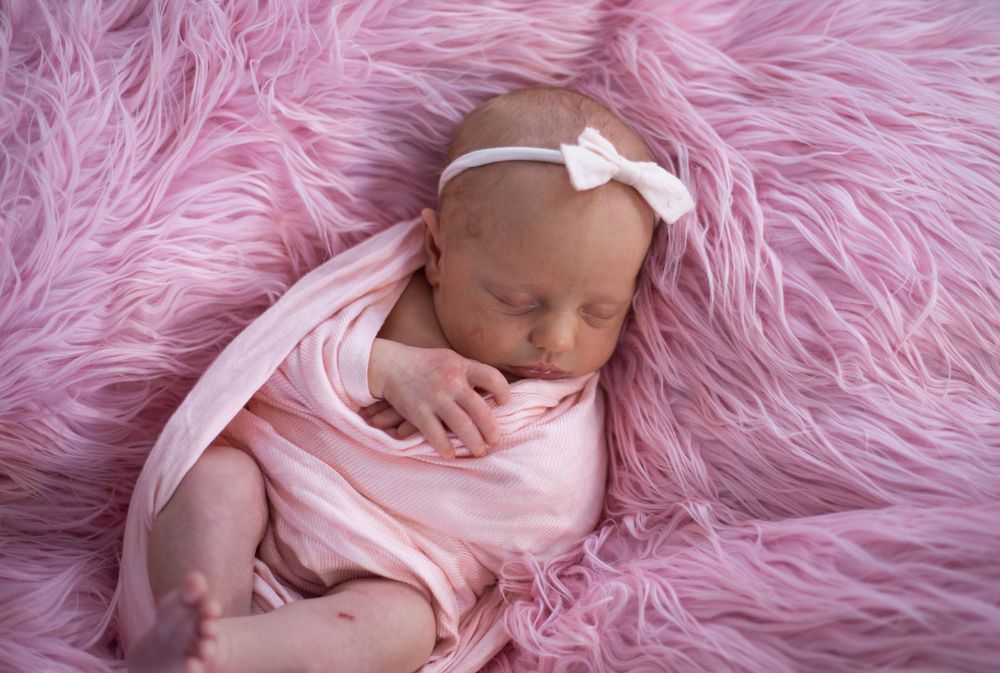 Newborn photography session featuring baby on pink fluffy fur textile backdrop. Mauston photographer.