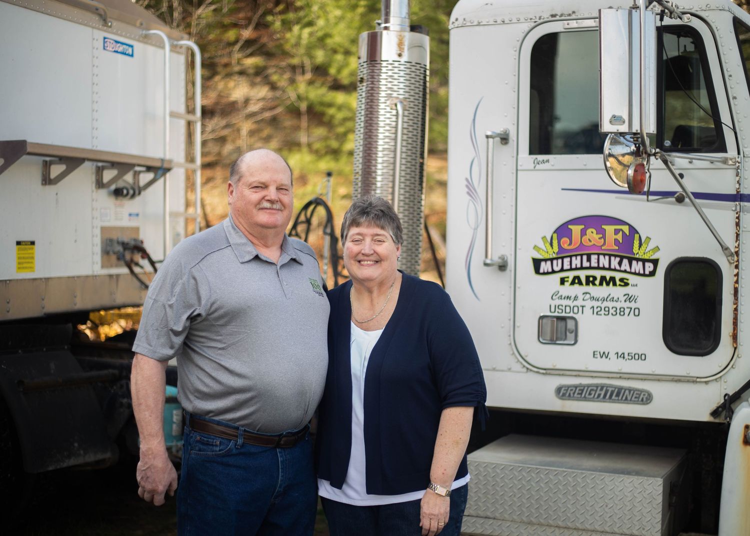People posing next to a white delivery truck with farm business signage. Mauston photographer.