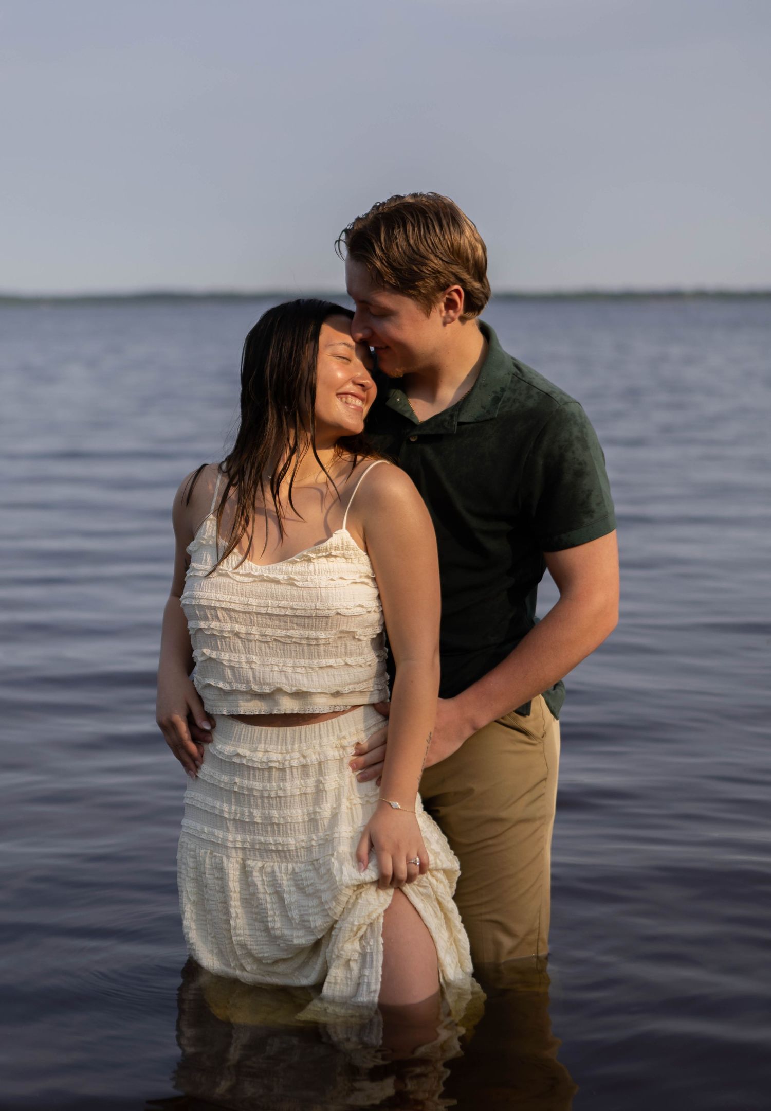 Romantic couple embracing in water during lakeside photoshoot. Mauston photographer.