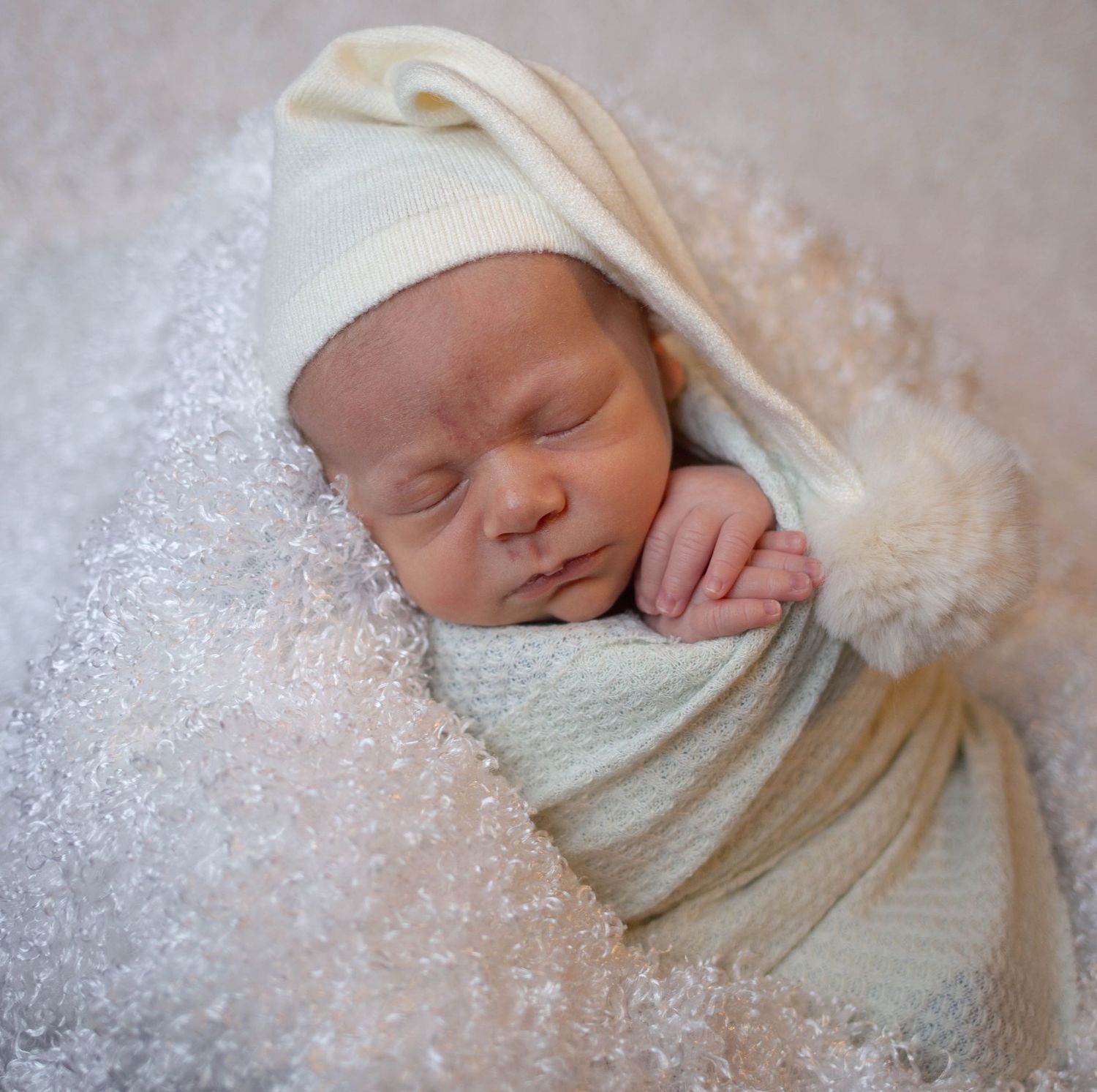 Artistic newborn portrait with baby wrapped in cream colored swaddle against sparkly background. Mauston photographer.