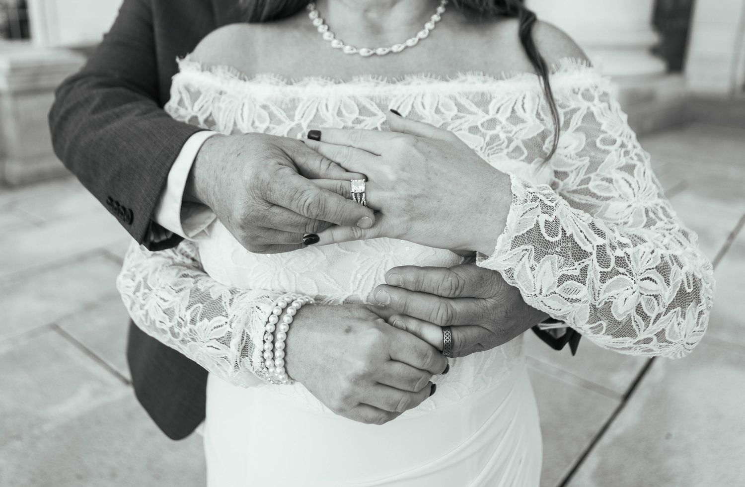 Close-up detail of hands with wedding rings against delicate white lace sleeves. Mauston photographer.