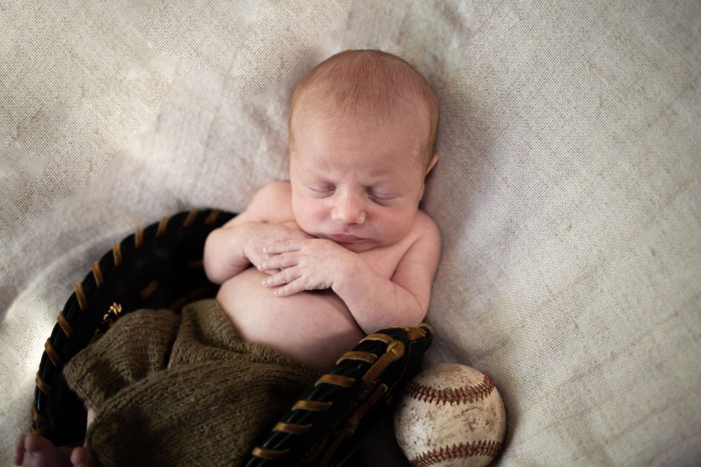 Newborn baby sleeping peacefully on soft cream-colored blanket in natural light. Mauston photographer.