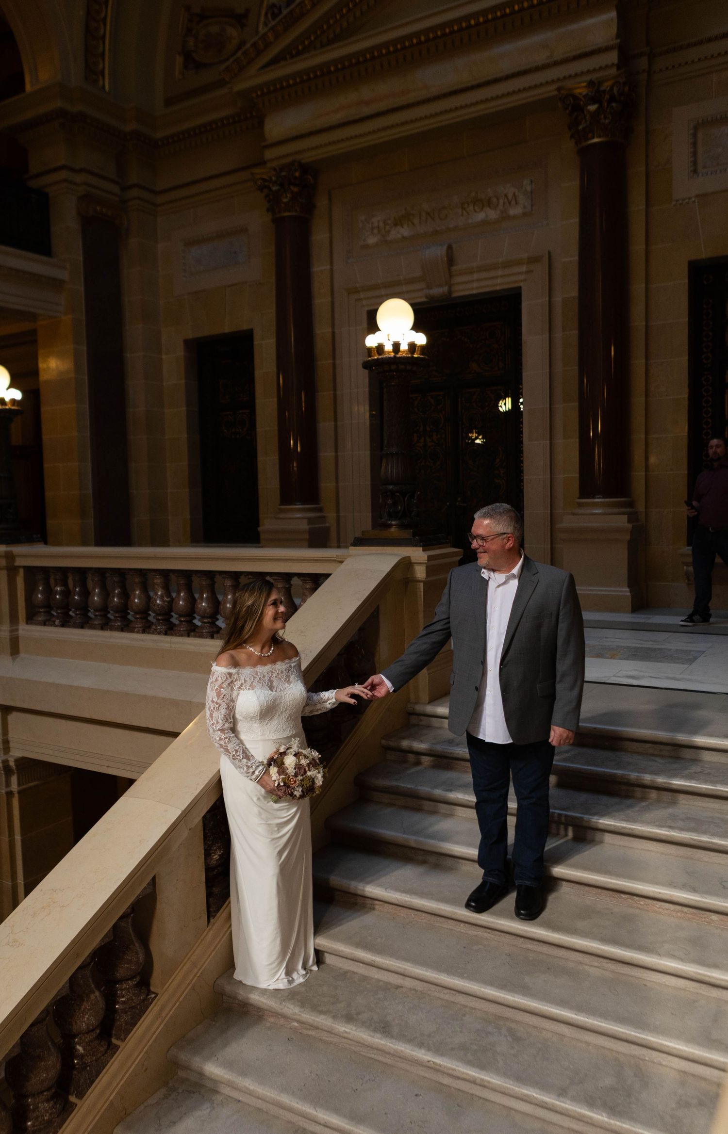 Elegant couple posing on marble steps inside historic building. Mauston photographer.